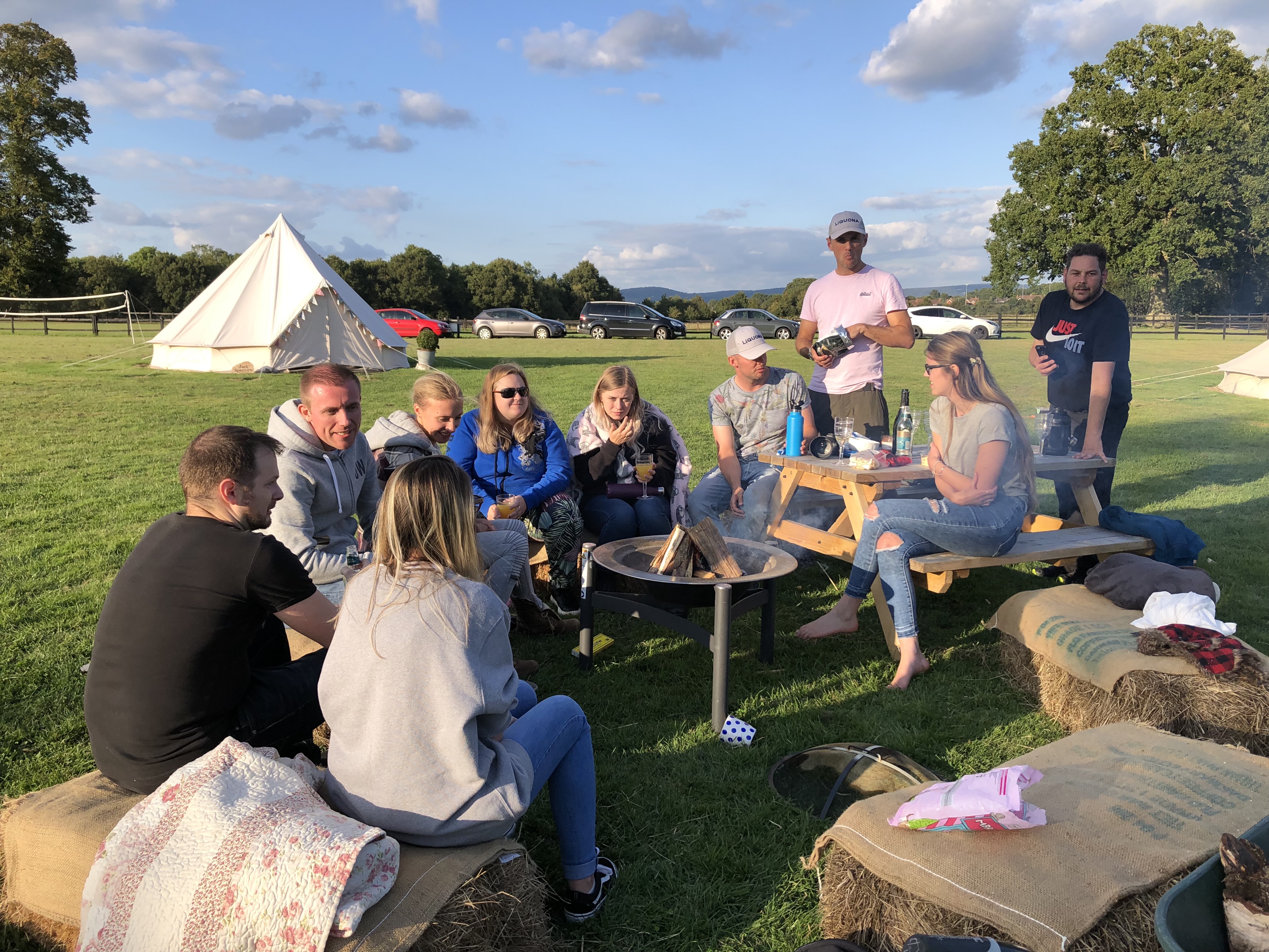 Glamping field with tents and campfire, ideal for team-building and networking events.