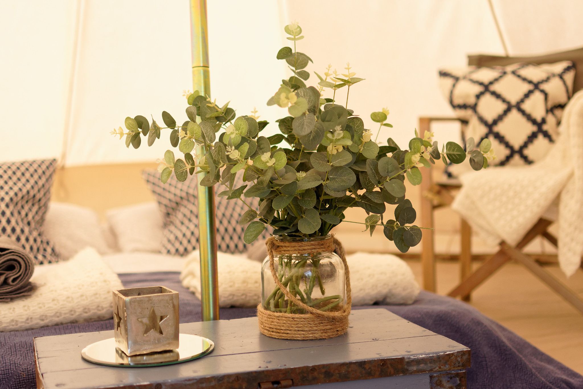 Glamping field event space with rustic table and cozy seating for intimate gatherings.