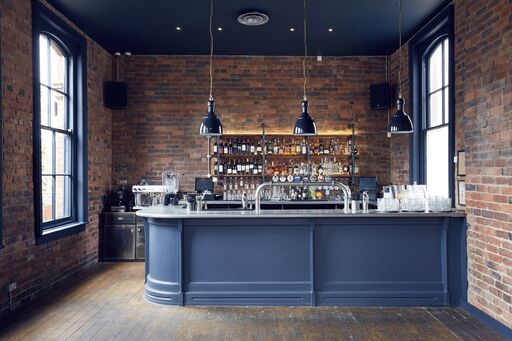 Stylish Upstairs Bar with rustic brick backdrop, ideal for cocktail receptions and networking.