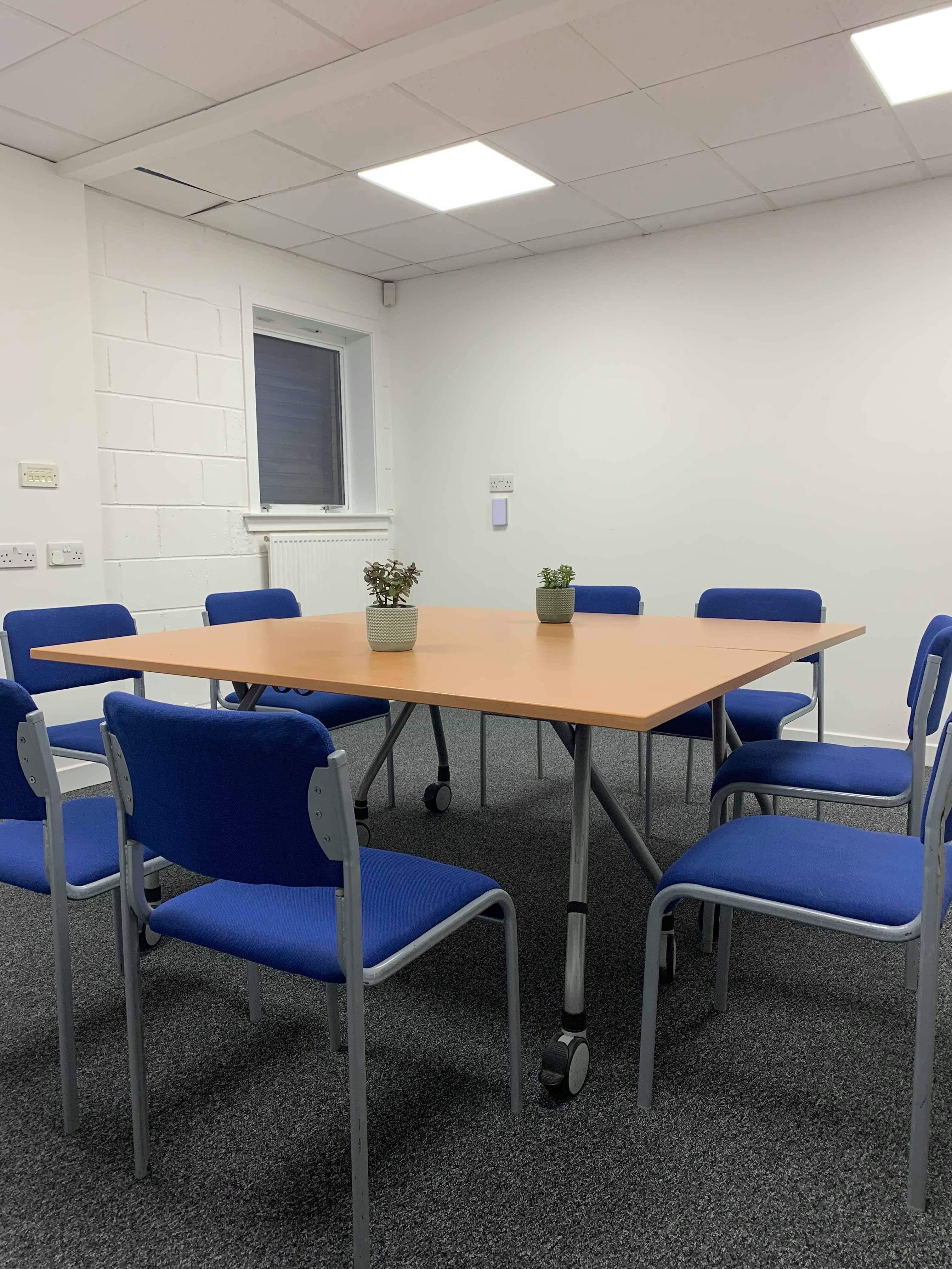 Auditorium in C7 Conference Centre with square table and blue chairs for meetings.