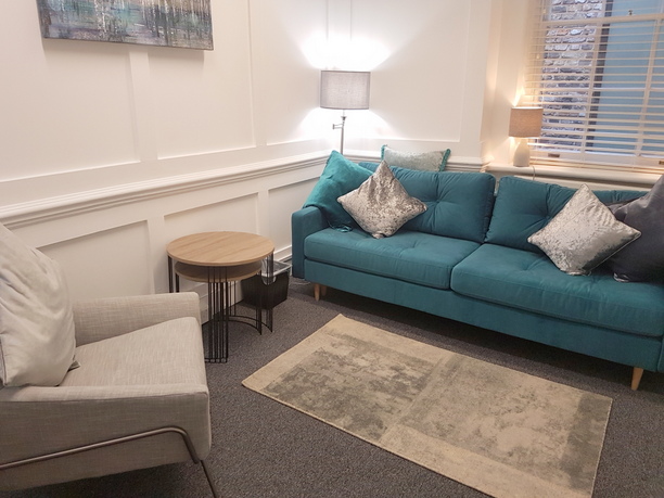 Cozy lounge in The Bow Suite, ideal for networking events with teal sofa and soft lighting.