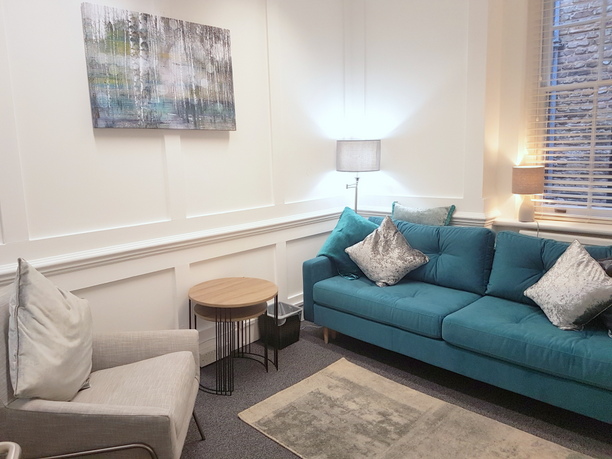 Cozy meeting space in The Bow Suite with teal sofa for casual gatherings and brainstorming.