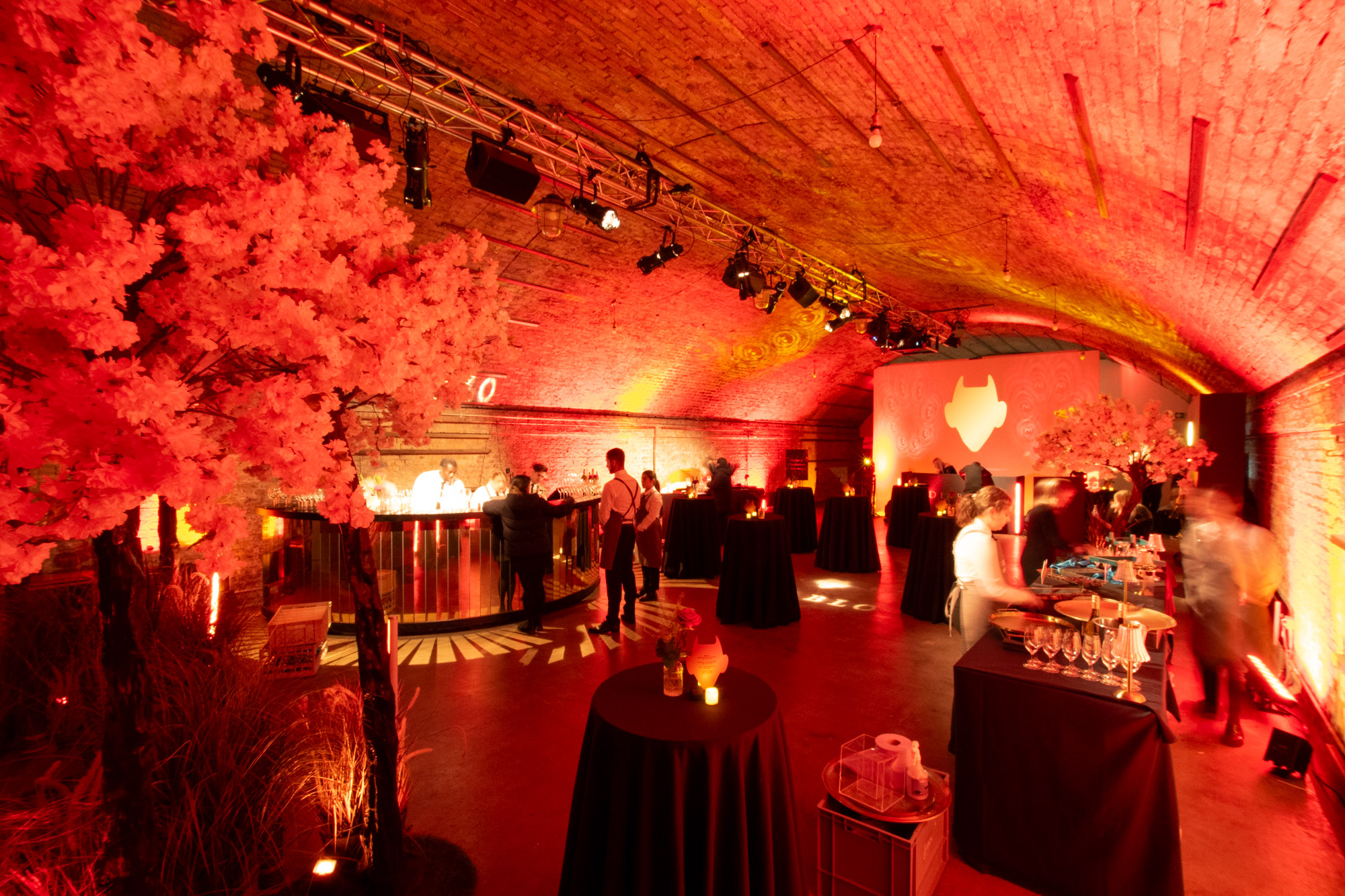 Vibrant event space with red lighting, ideal for networking and celebrations.