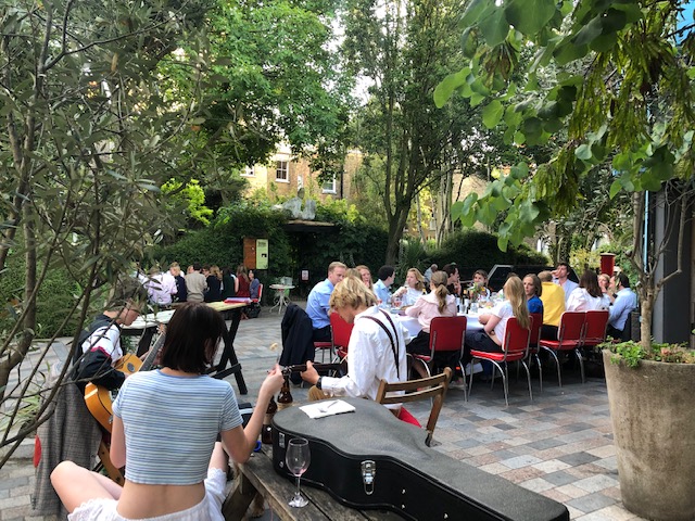 Outdoor event setup at Italo Delicatessen with greenery, perfect for networking gatherings.