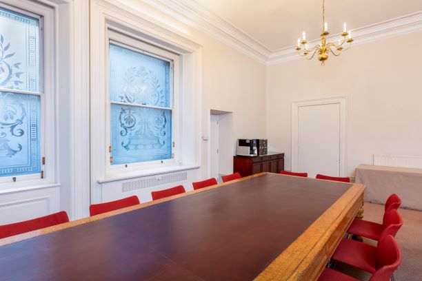 Arthur Holmes Room with wooden table and red chairs, ideal for corporate meetings and events.