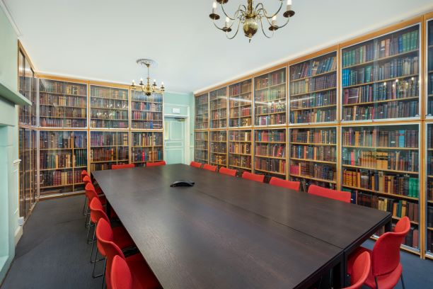 William Buckland Room with dark wooden table and red chairs, ideal for meetings and events.