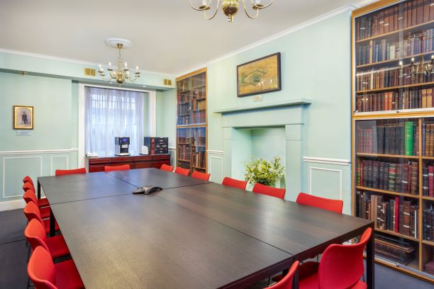 William Buckland Room with dark table and red chairs, ideal for meetings and events.