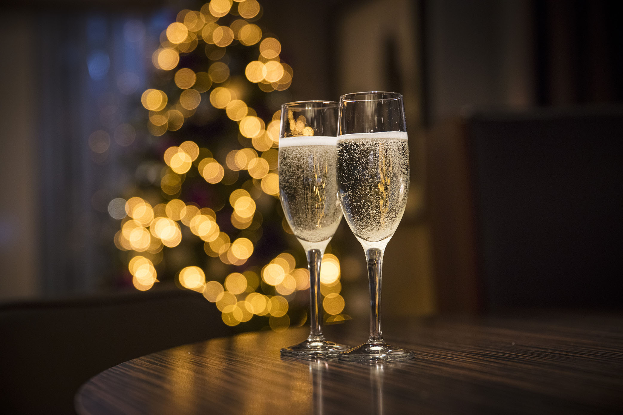 Champagne flutes with holiday lights, ideal for festive celebrations and year-end events.