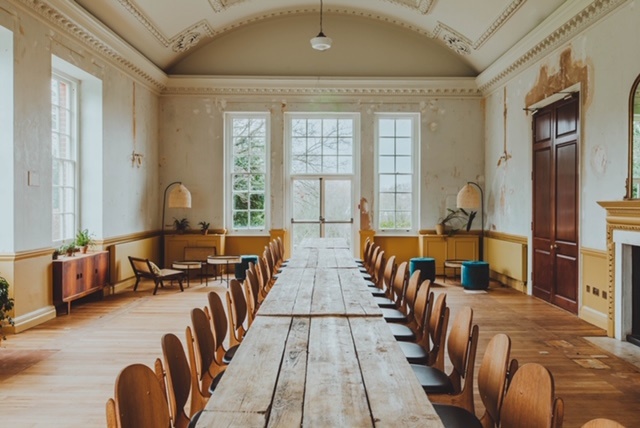 Spacious meeting room with wooden table, ideal for collaborative discussions and events.