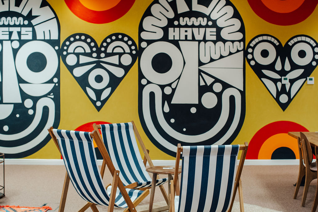 Vibrant meeting space with artistic murals and striped deck chairs for creative brainstorming.