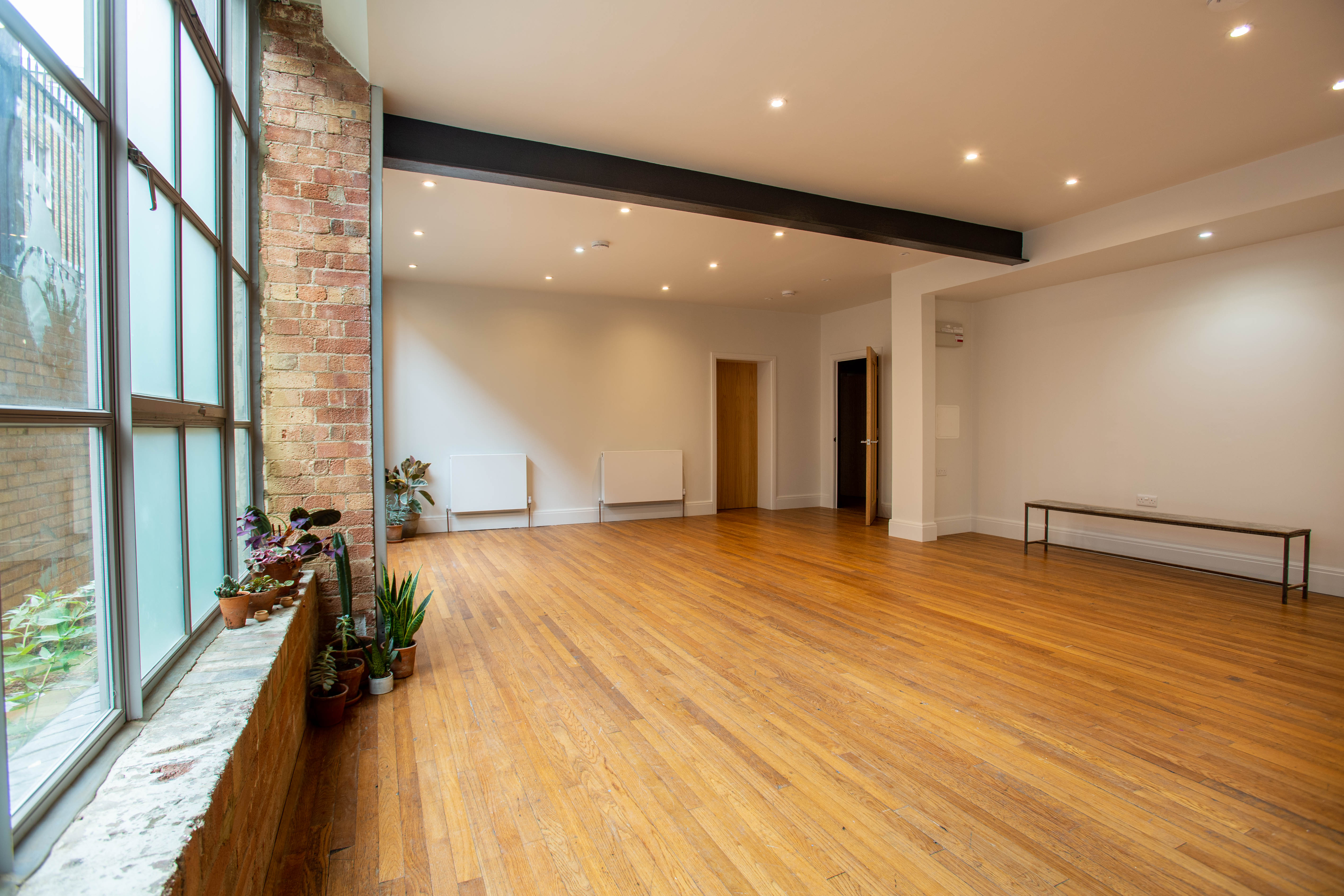 Versatile event space with natural light and wooden flooring, perfect for workshops and gatherings.