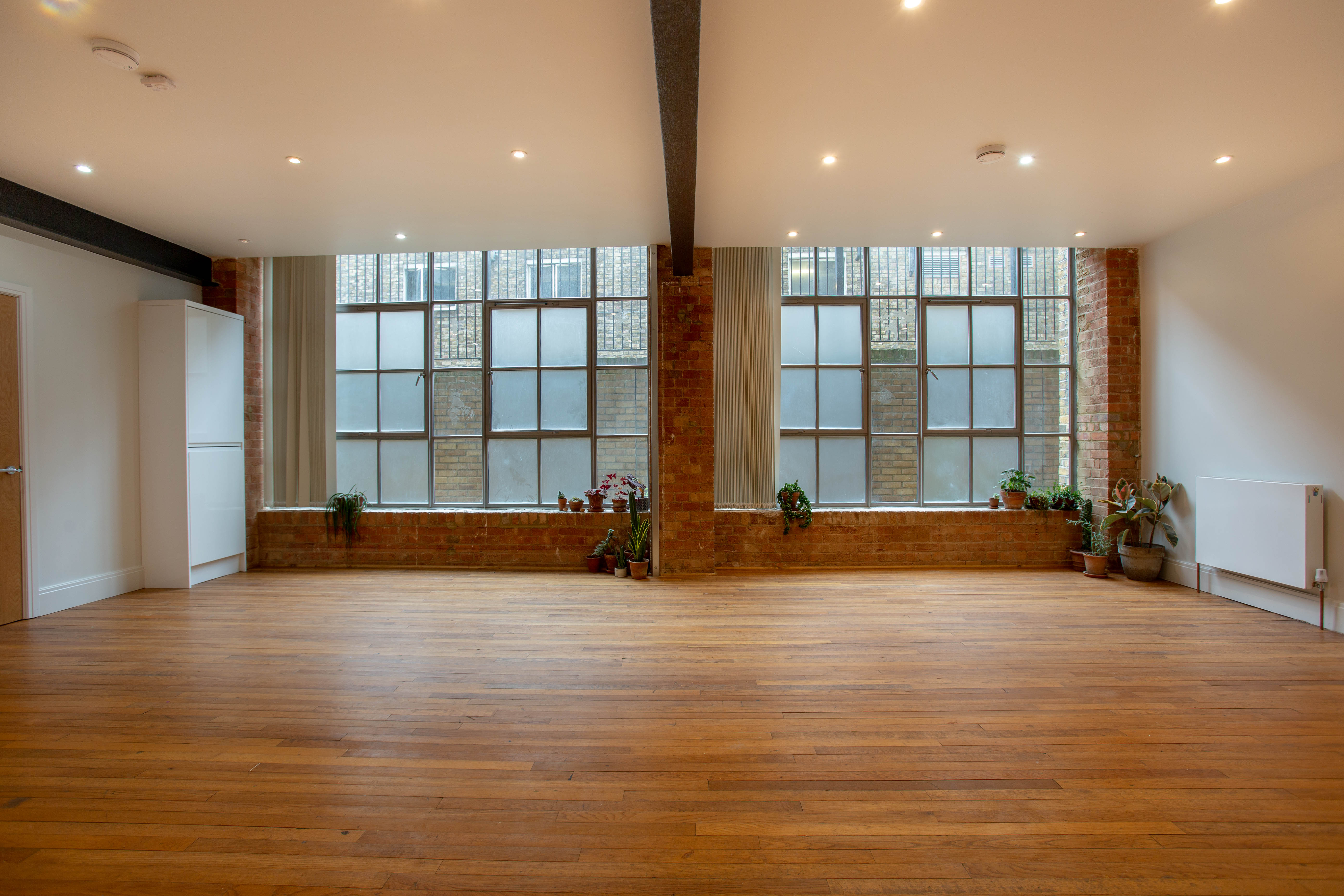Spacious, well-lit event venue with wooden flooring for workshops and presentations.