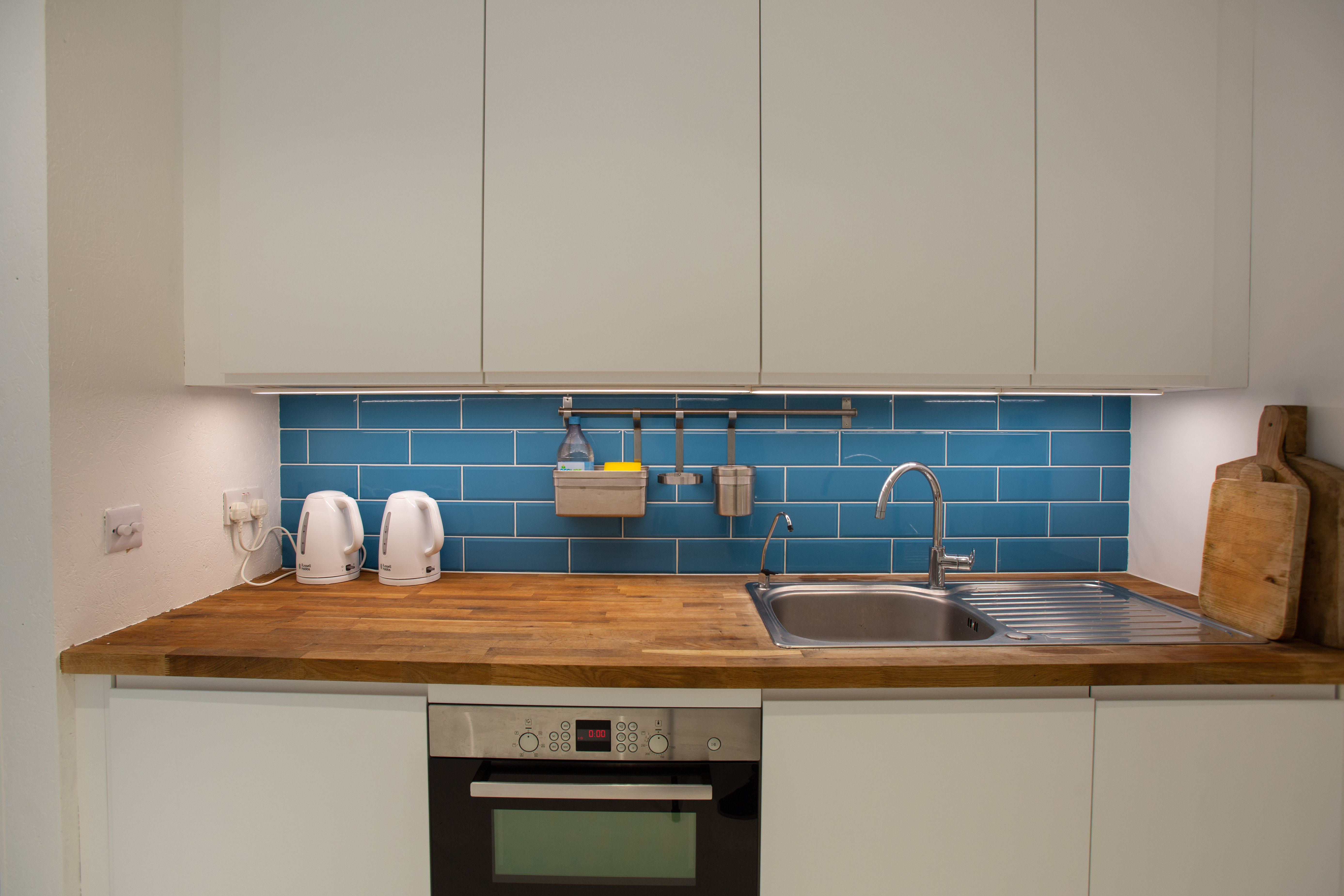 Modern kitchenette in Studio 52, featuring a blue backsplash for events and meetings.