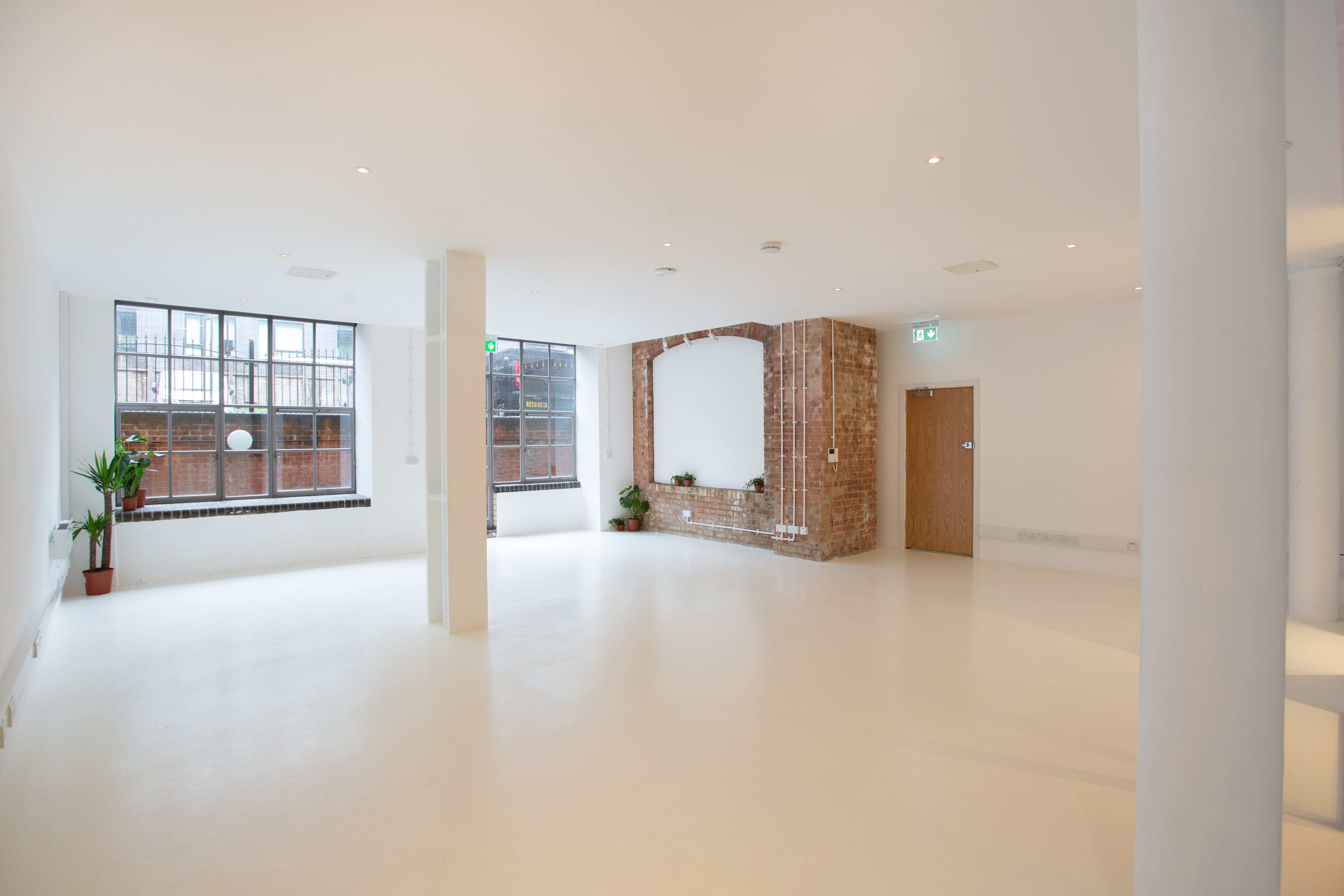 Versatile event space with natural light and brick feature, perfect for workshops and meetings.