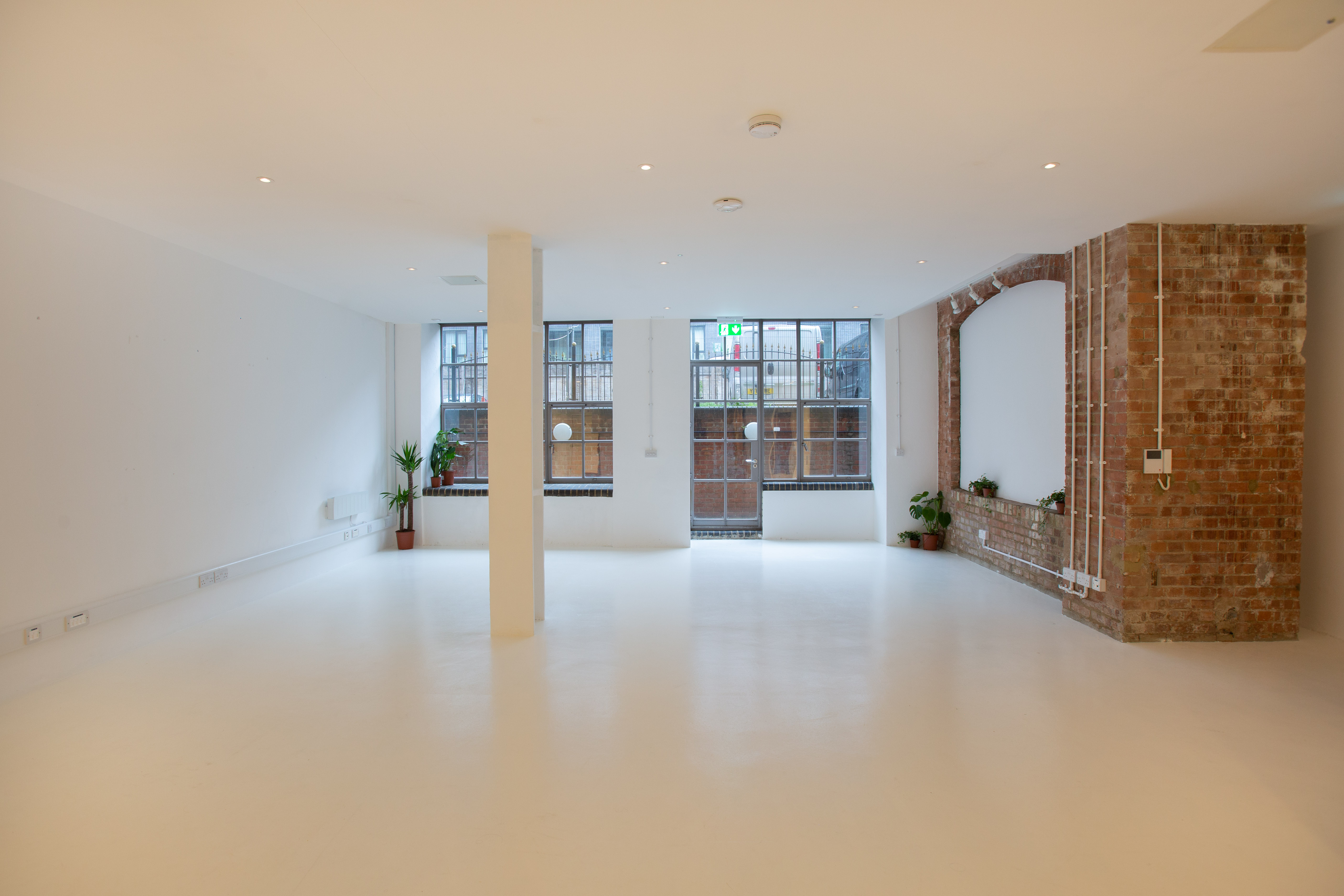 Versatile event space with natural light and exposed brick, ideal for meetings and workshops.