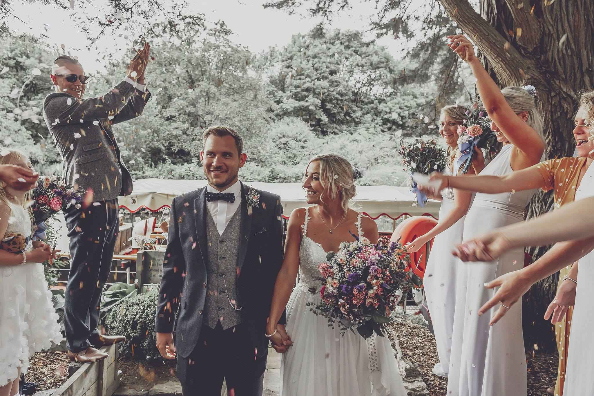 Joyful wedding celebration at Beeses Riverside Bar with confetti and smiling guests.