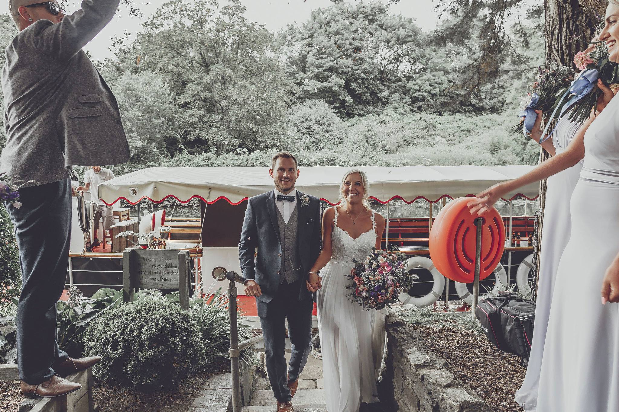 Joyful couple celebrating wedding at Beeses Riverside Bar with scenic outdoor backdrop.