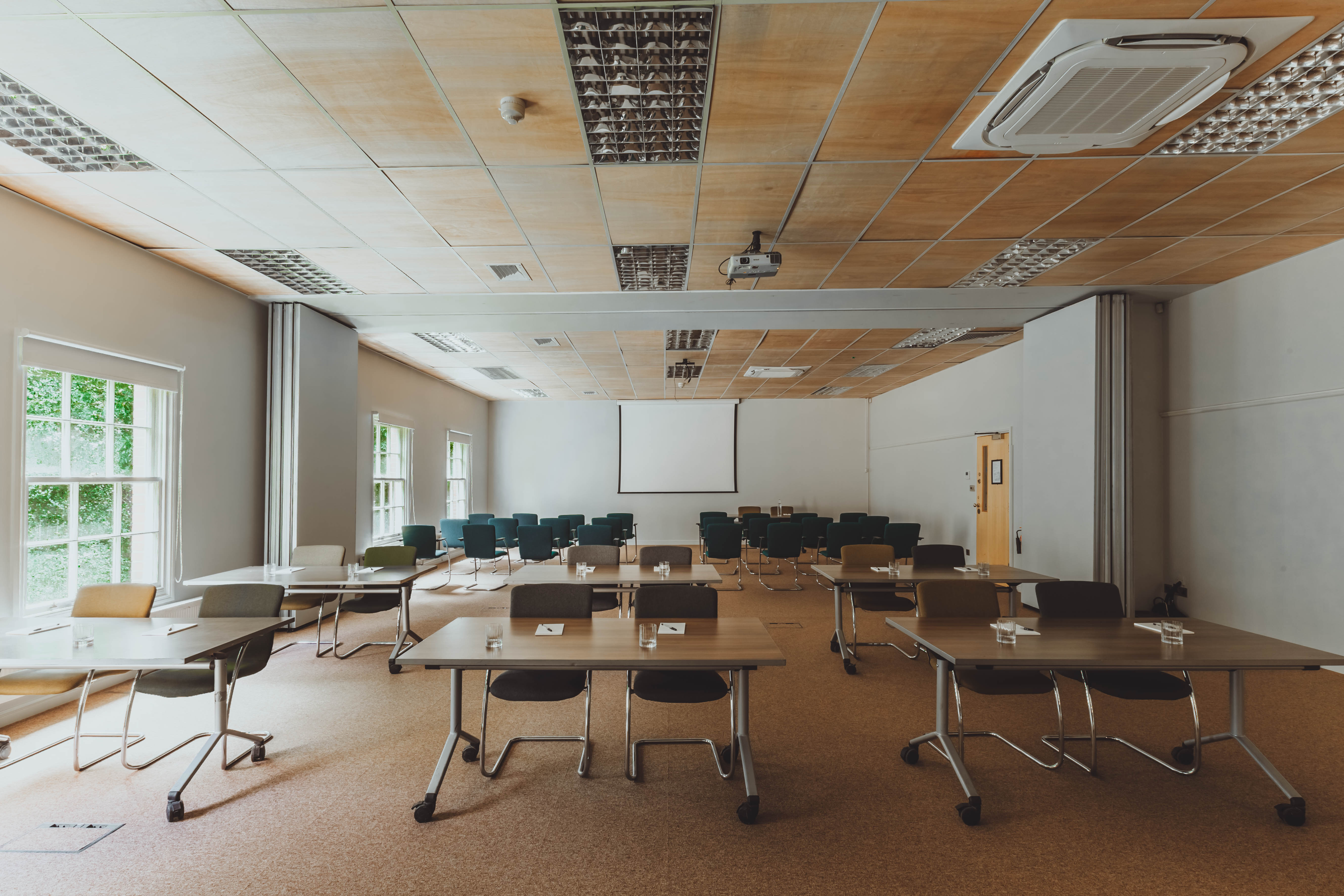 Versatile meeting space with projector screen, ideal for workshops and training sessions.