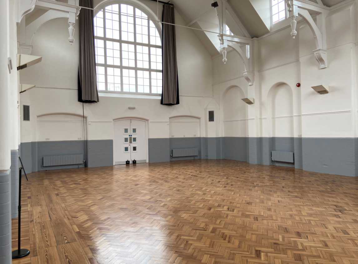 Spacious Milford Hall with polished wooden floors, ideal for events and workshops.