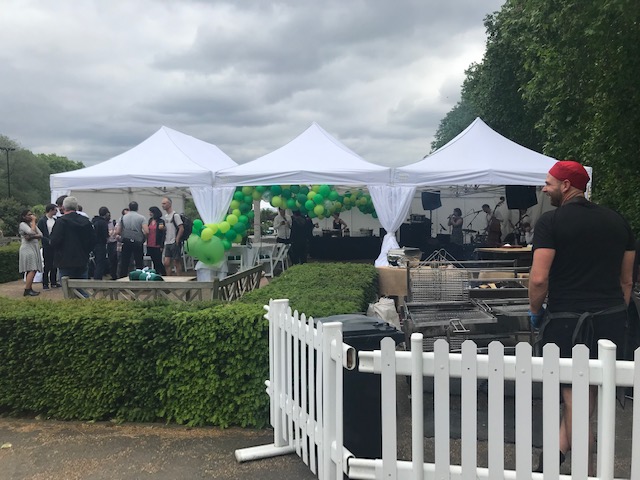 Vibrant outdoor event at Pavilion Gardens with white tents and green balloons.