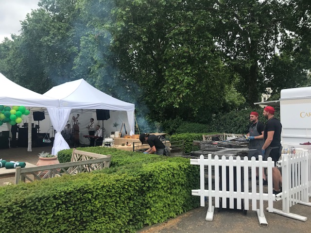 Outdoor event setup at Pavilion Gardens with a white tent and barbecue area.