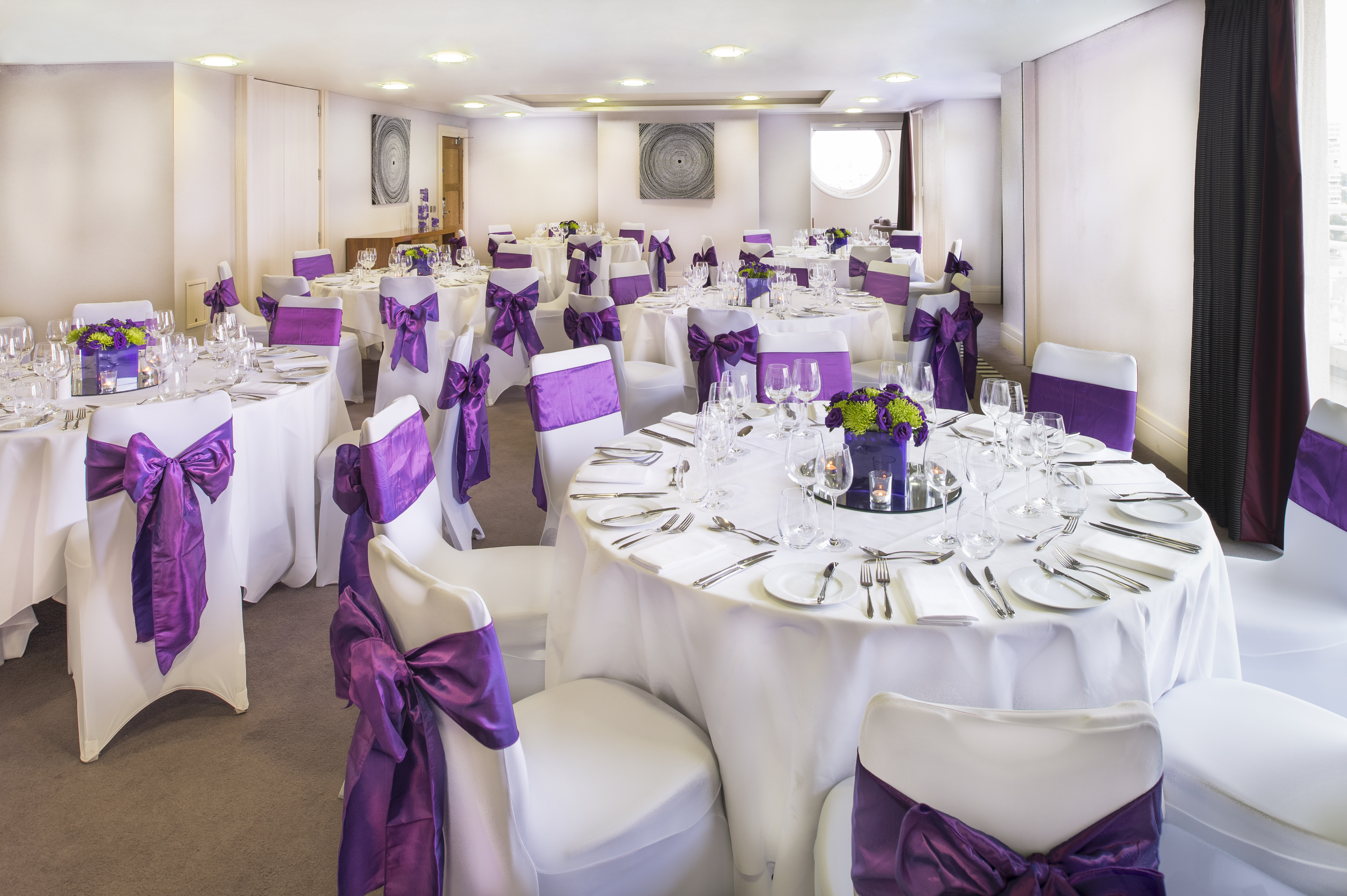 Bridges Suite at Chelsea Harbour Hotel, elegant event space with round tables and purple sashes.
