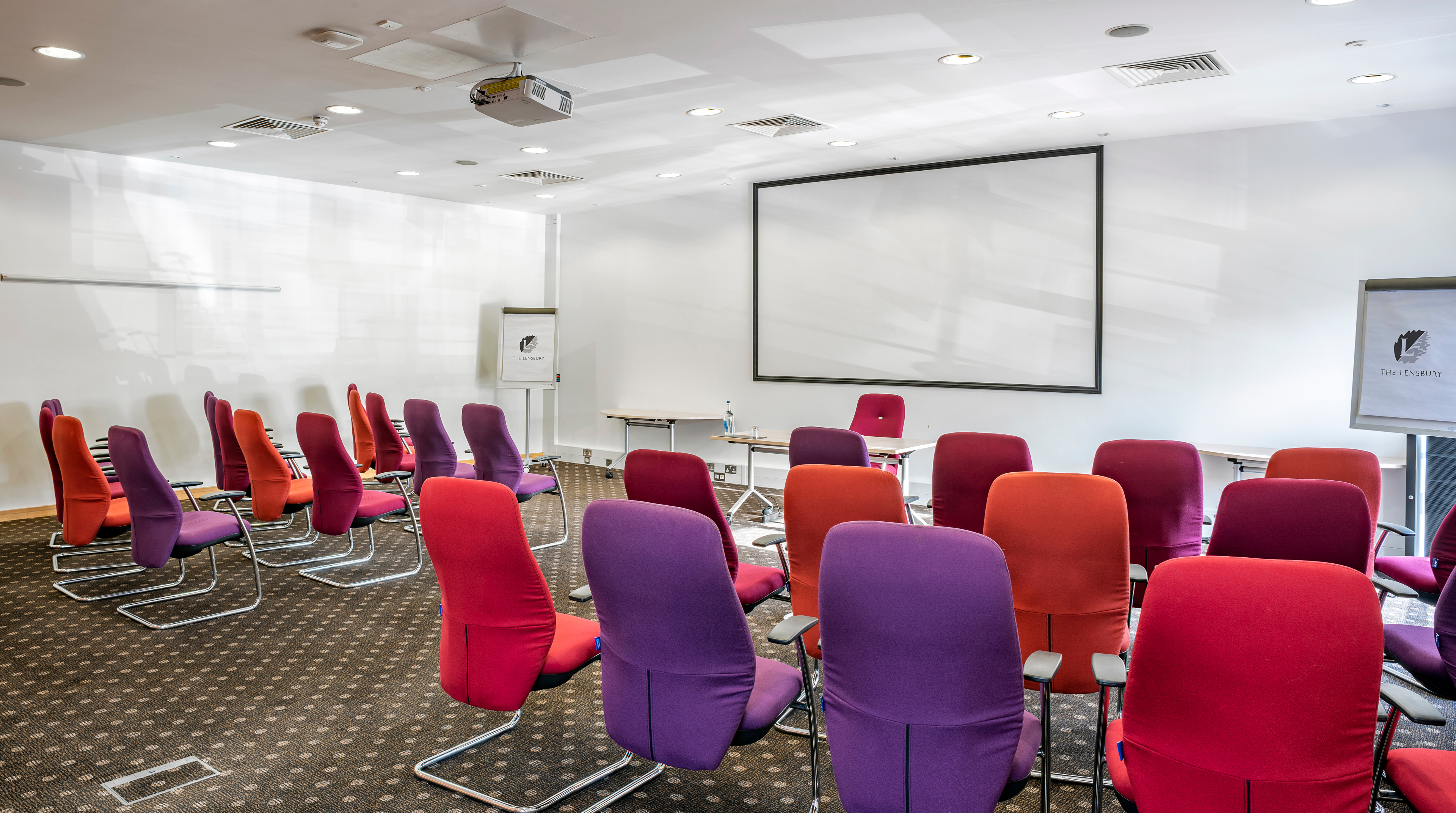 Modern meeting room with colorful chairs for engaging workshops at The Lensbury.