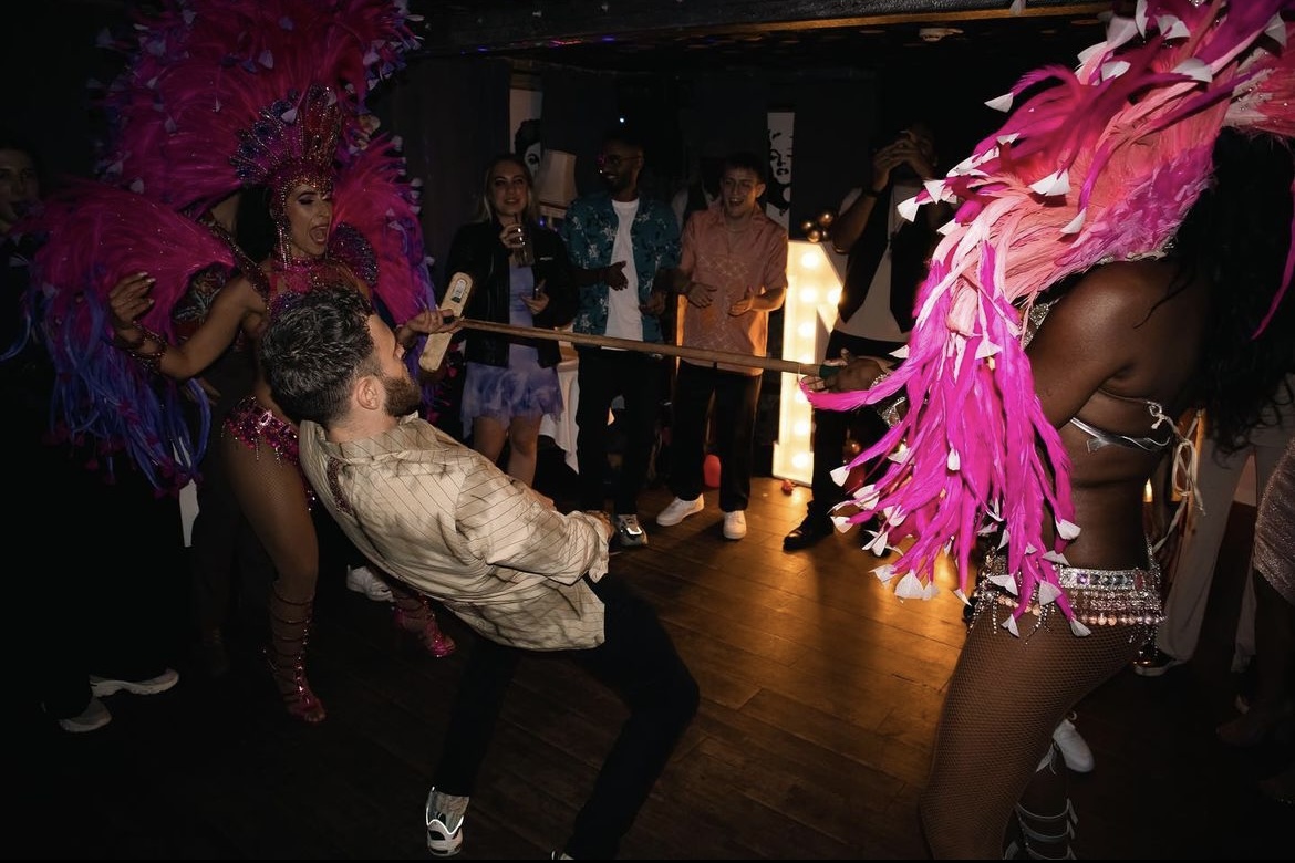 Vibrant event at The Hamlet Vinyl Bar with performers in colorful costumes and limbo challenge.