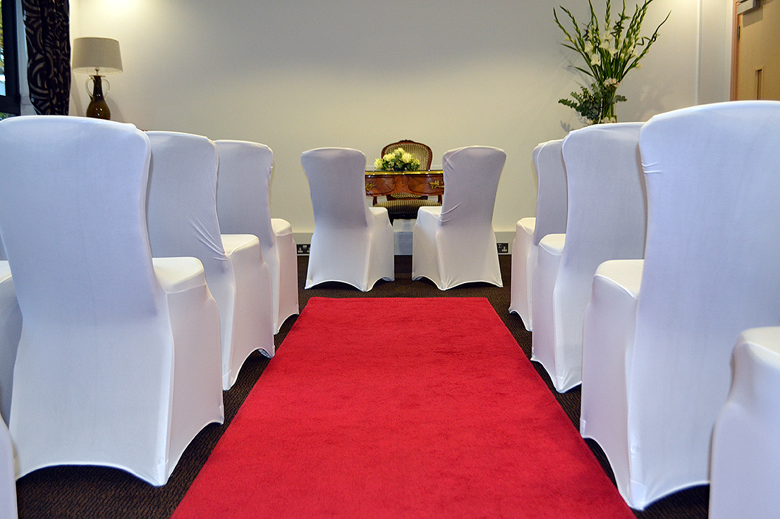 Elegant Mortimer Room event space with white-covered chairs and red carpet for ceremonies.