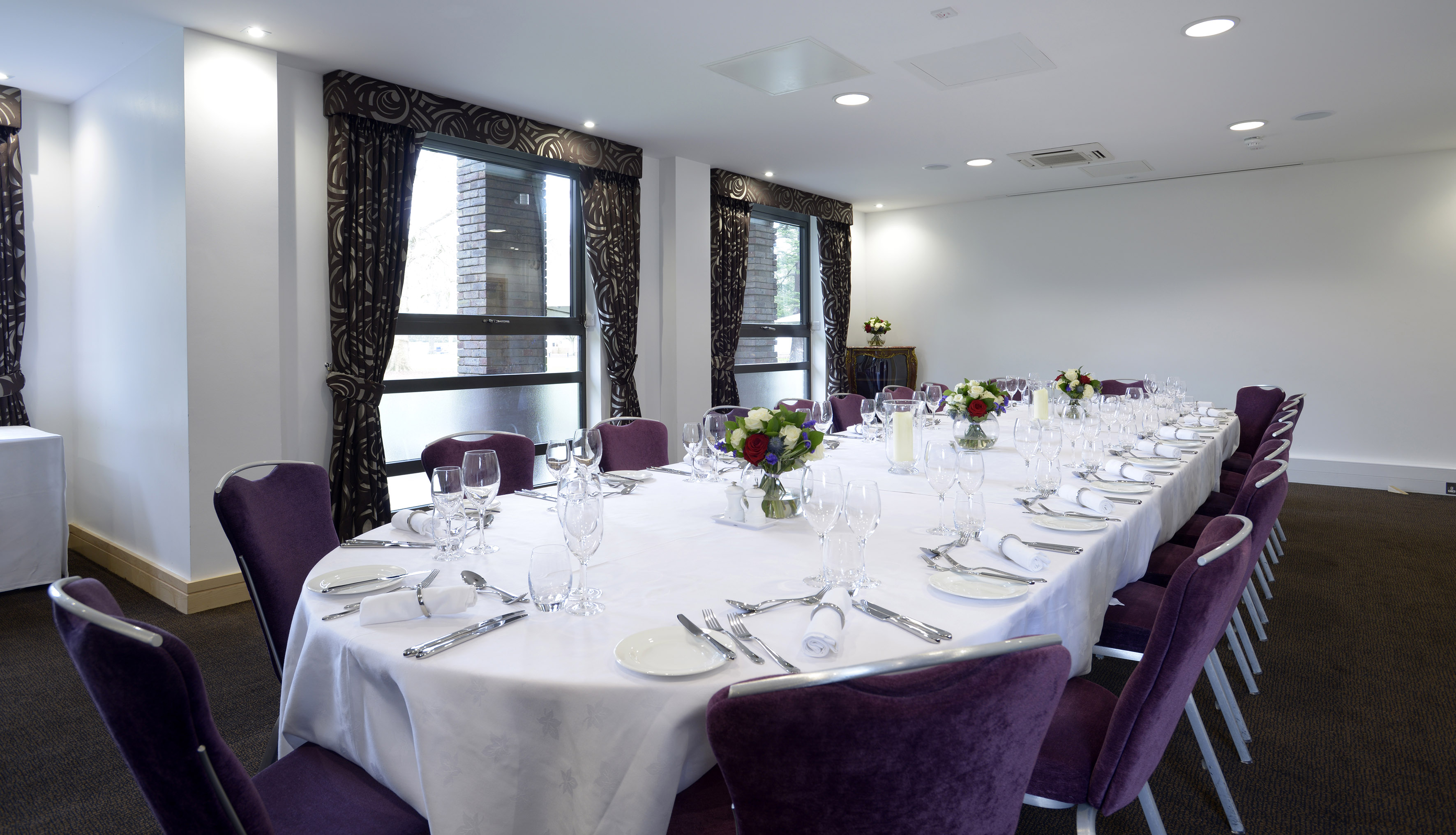 Elegant Mortimer Room dining setup with white linens and purple chairs for corporate events.