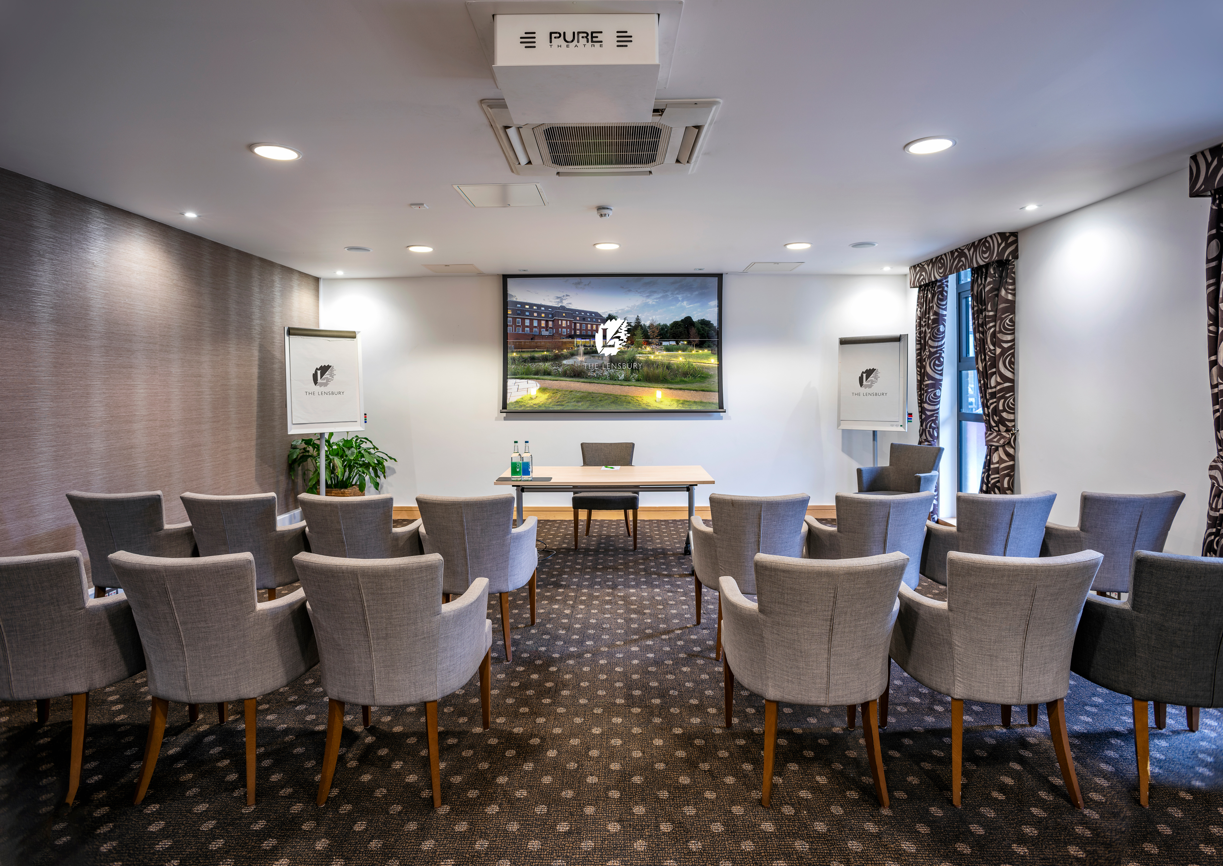 Lloyd Room at The Lensbury: professional meeting space with large screen for presentations.