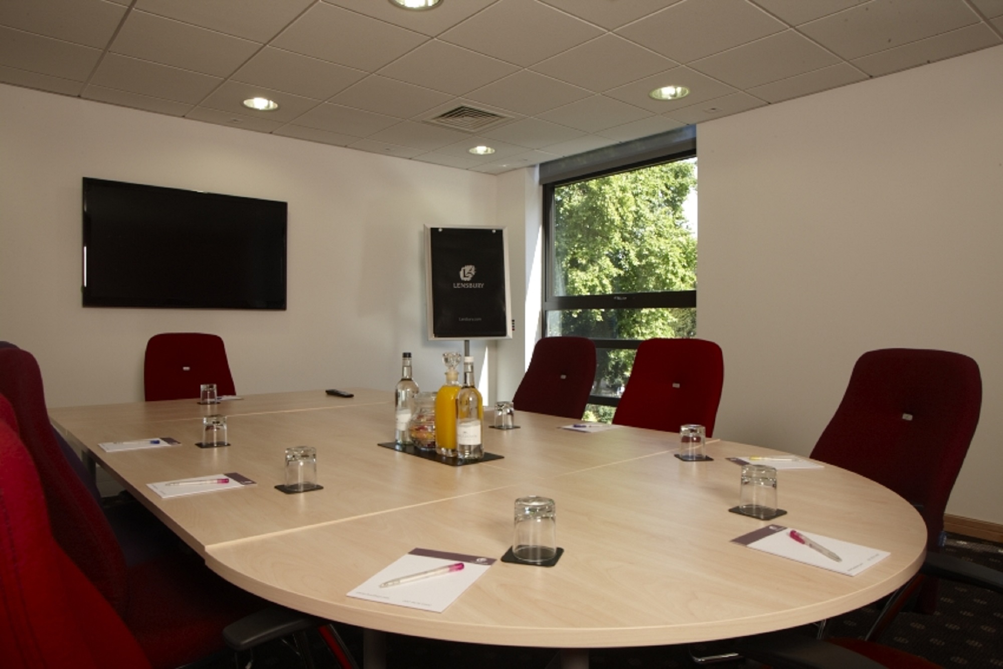 Doherty Room at The Lensbury: oval table, red chairs, ideal for meetings and events.