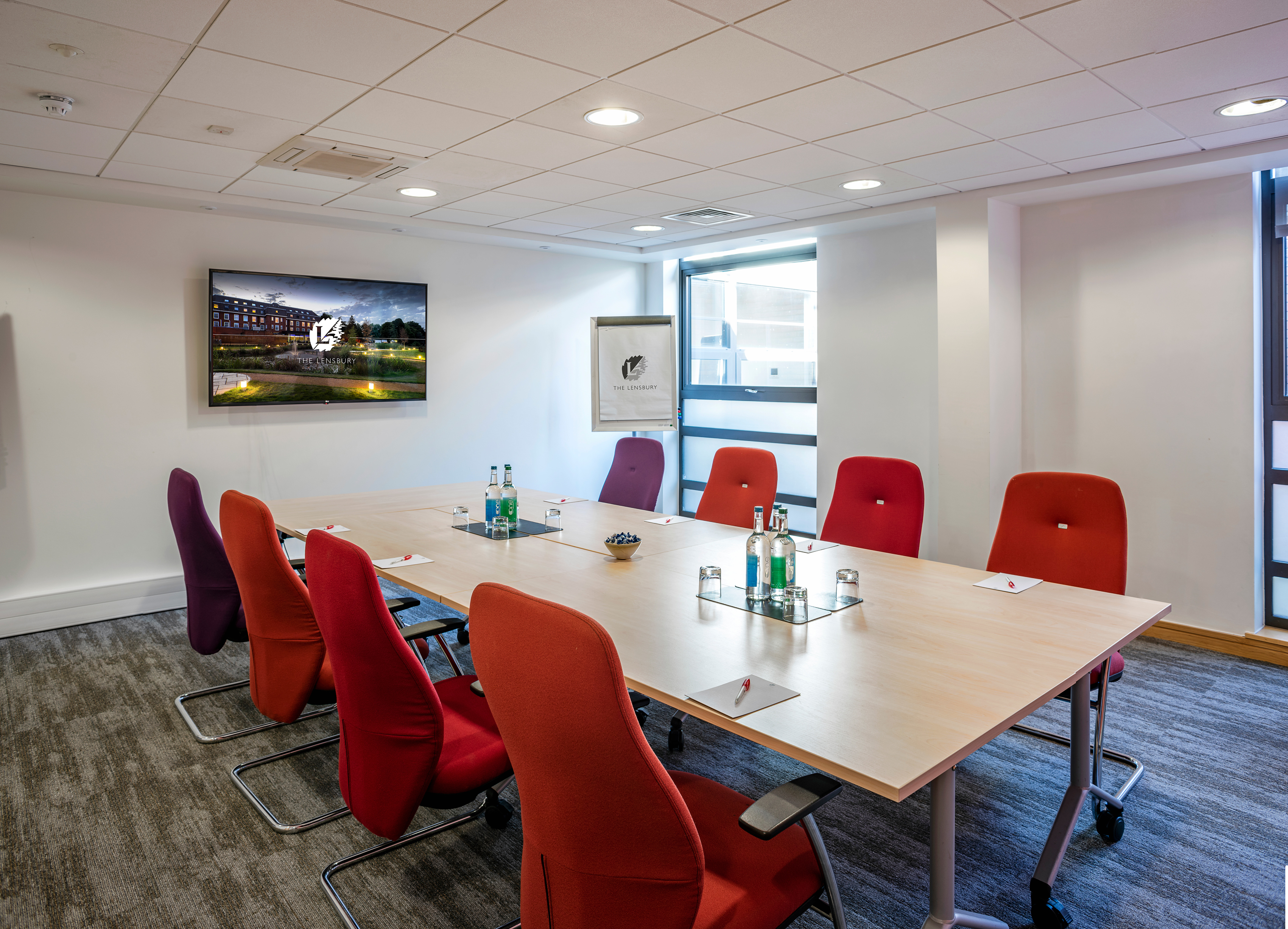 Modern Murray Room at The Lensbury with vibrant chairs, perfect for meetings and events.