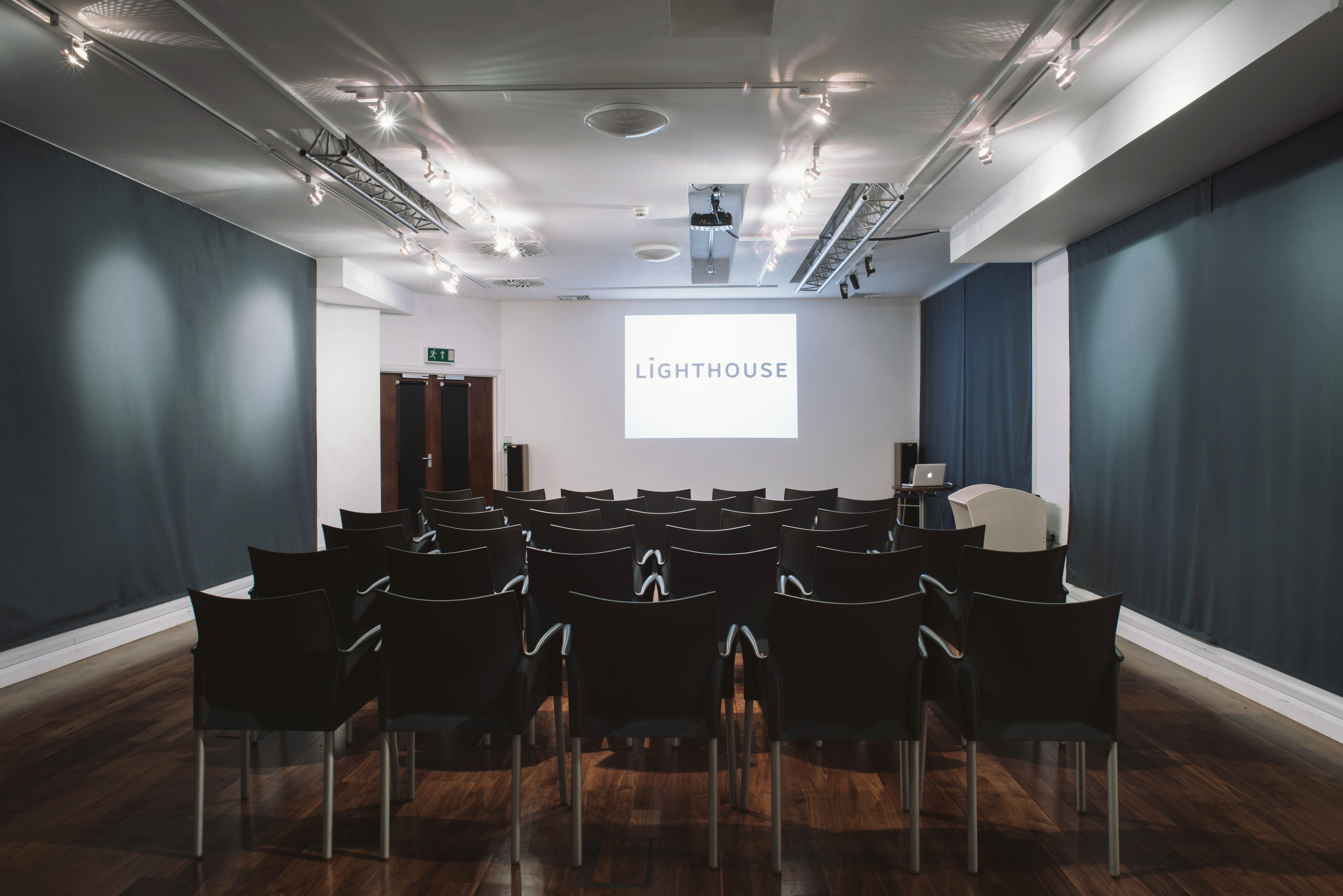 Digital Lounge meeting space with black chairs and presentation screen for engaging events.