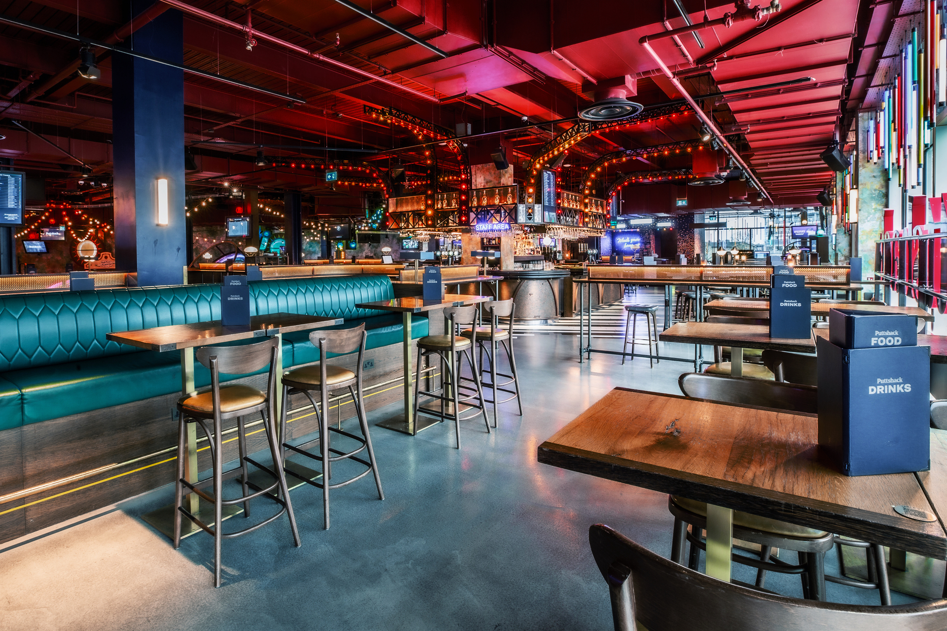 "Modern Christmas event space with vibrant decor and high-top tables at Puttshack White City."