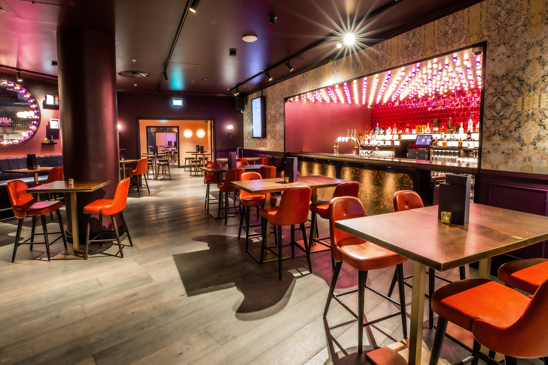 Christmas party at Puttshack Bank with vibrant red seating and modern decor.