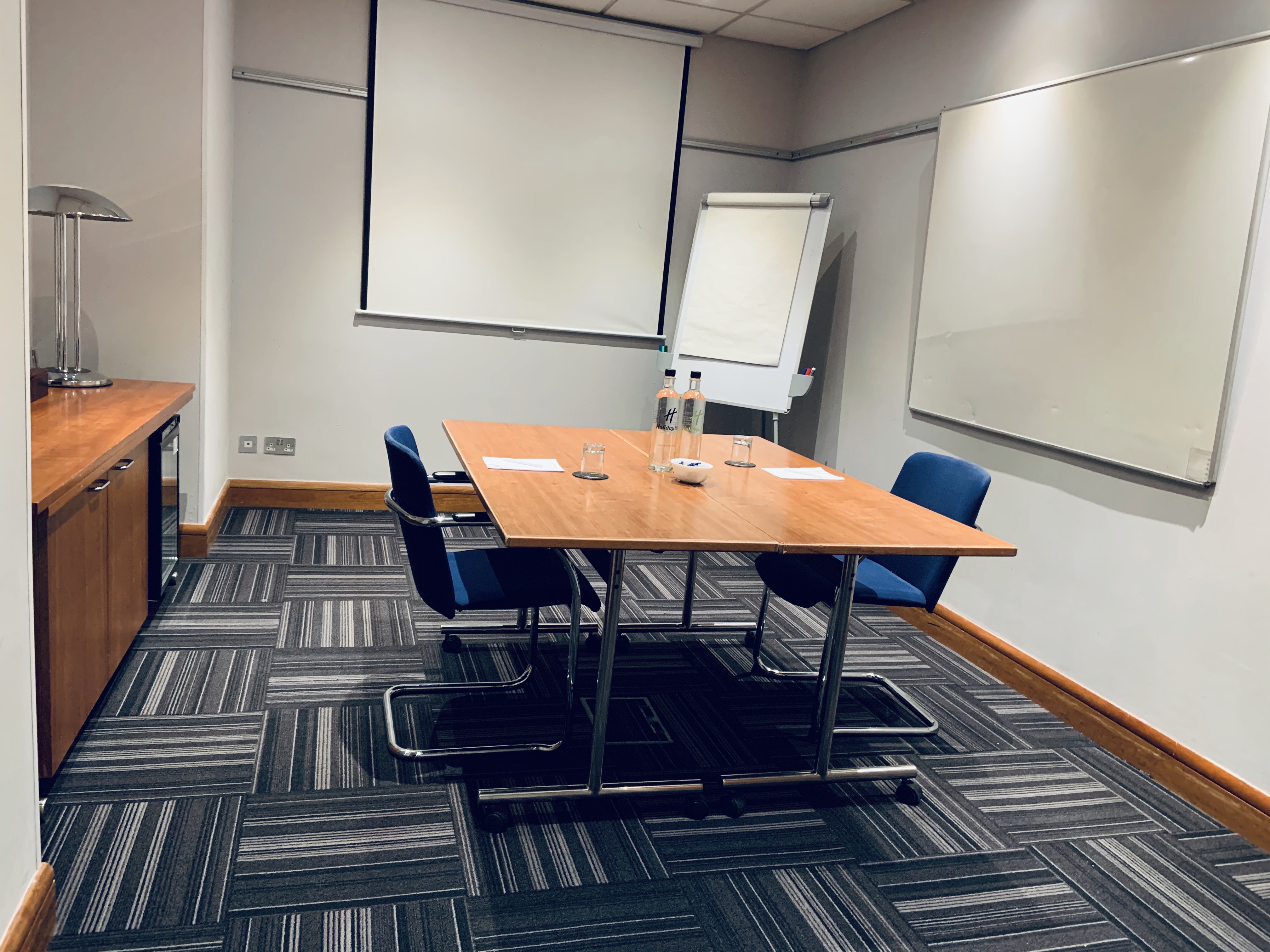 Small meeting room at Holiday Inn High Wycombe with wooden table, ideal for brainstorming sessions.