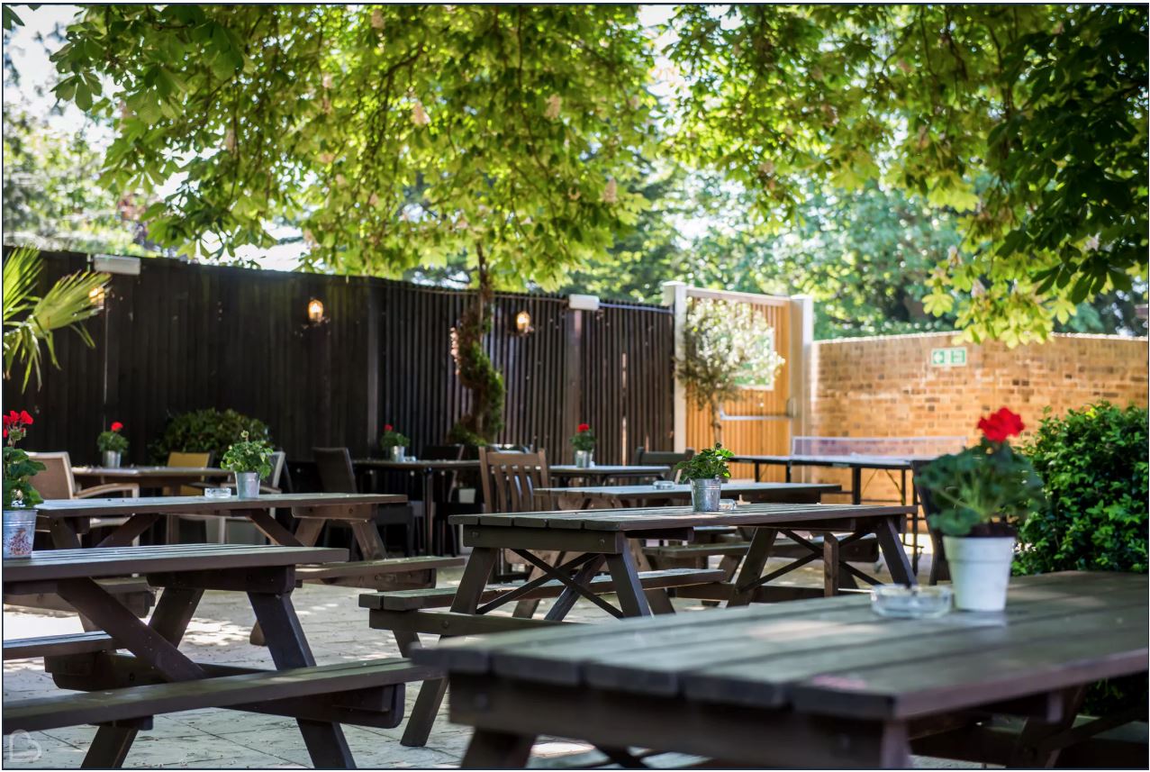 Outdoor garden venue with rustic tables, perfect for events and gatherings.