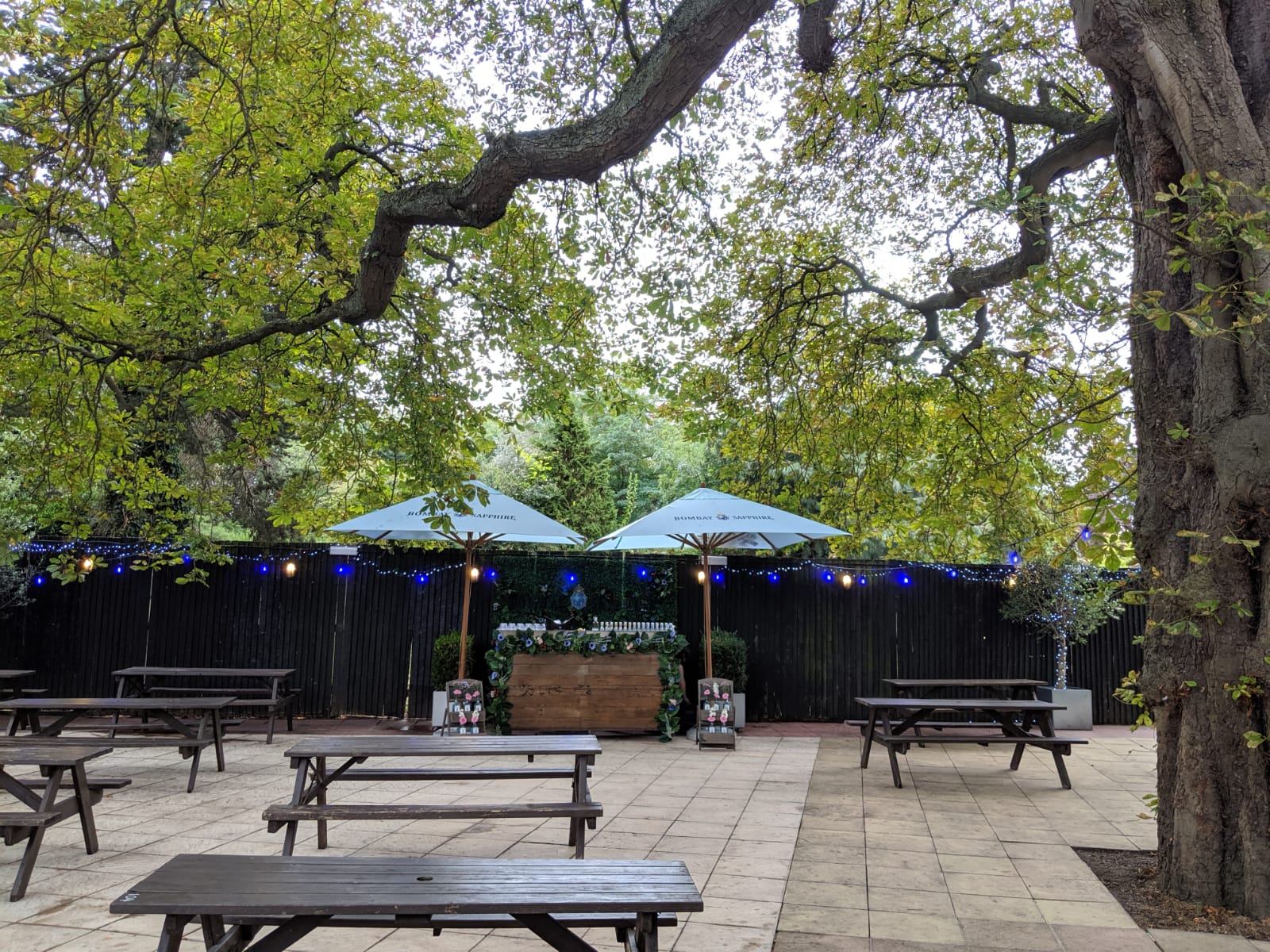 Outdoor garden event space with picnic tables, perfect for casual gatherings and networking.
