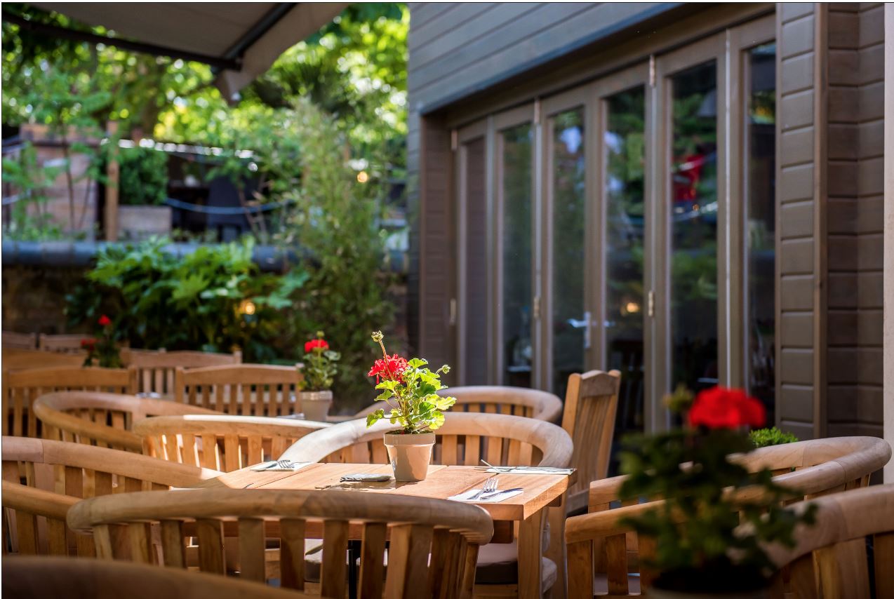 Outdoor dining at The Crown and Greyhound with wooden furniture, ideal for networking events.