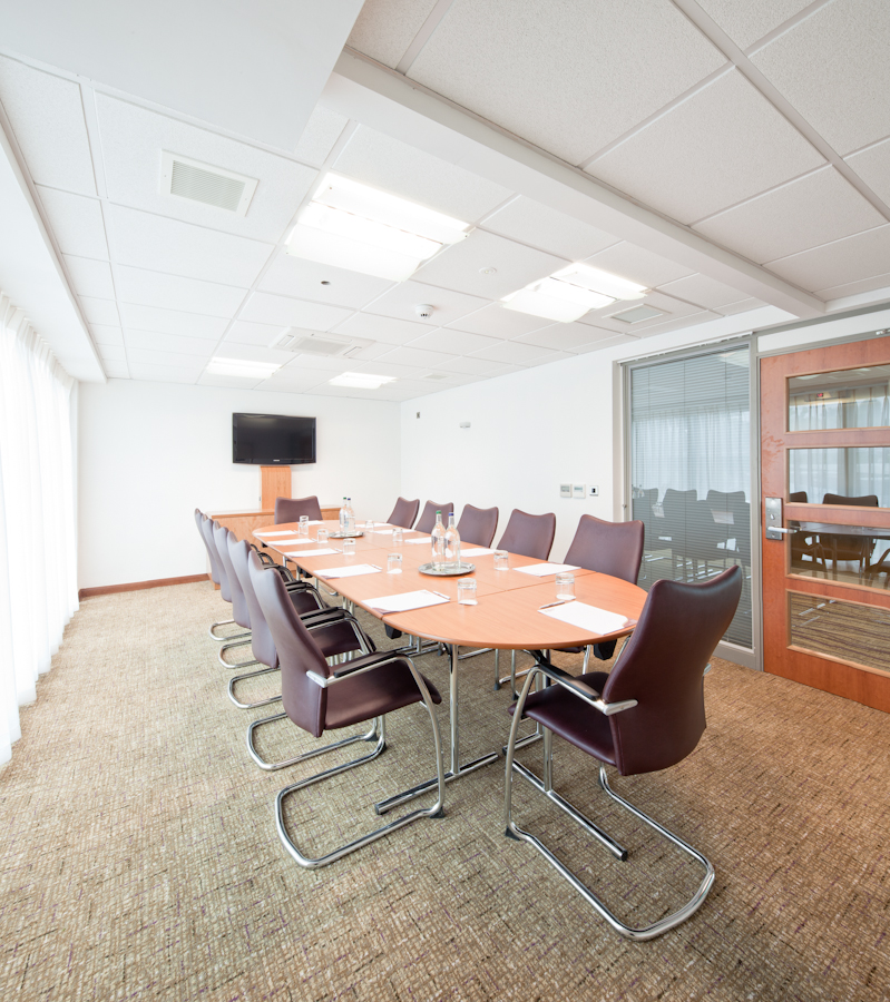 Modern meeting room with oval table at Drayton Manor Hotel for corporate events.