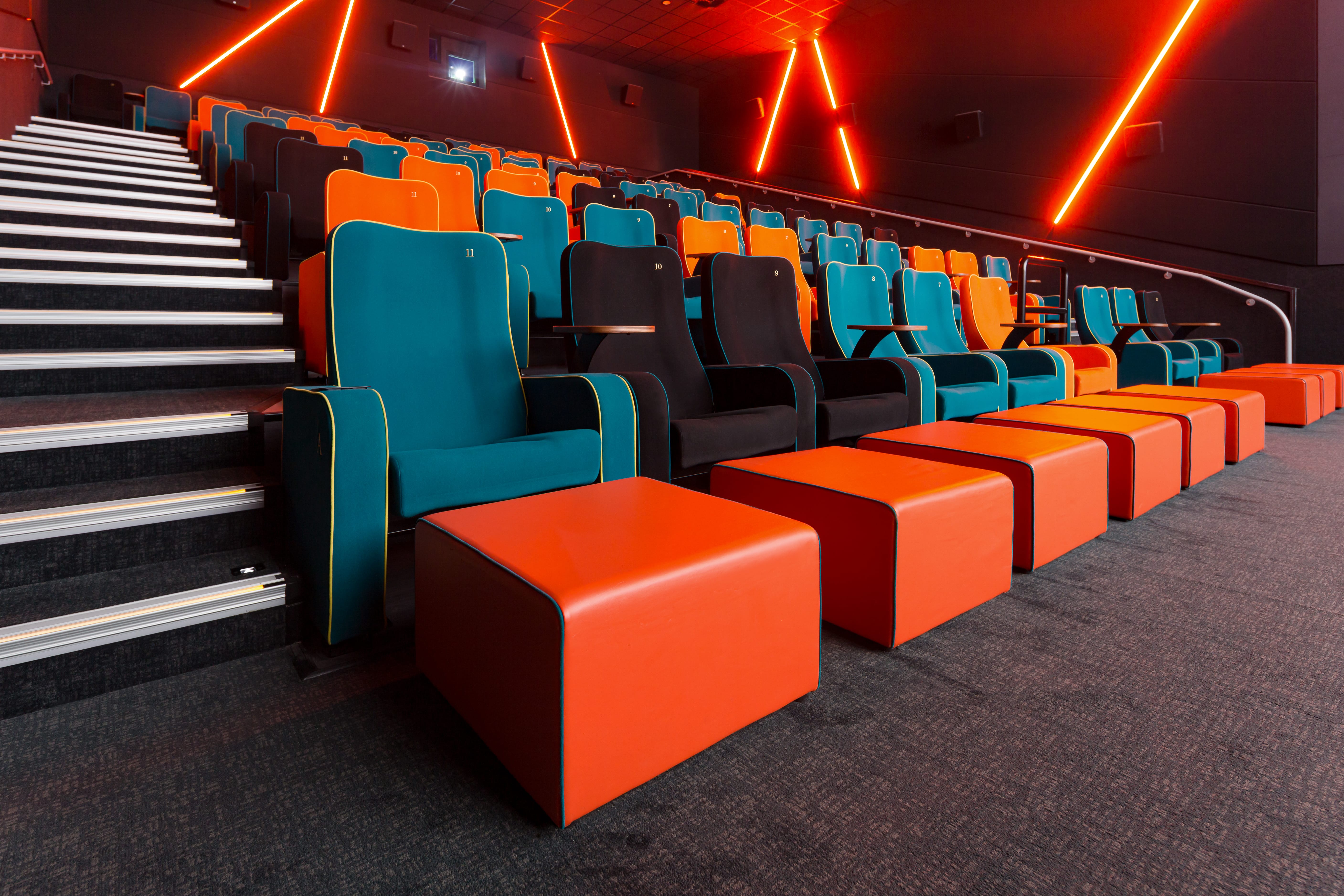Modern cinema auditorium with teal and orange seating, ideal for engaging film screenings.