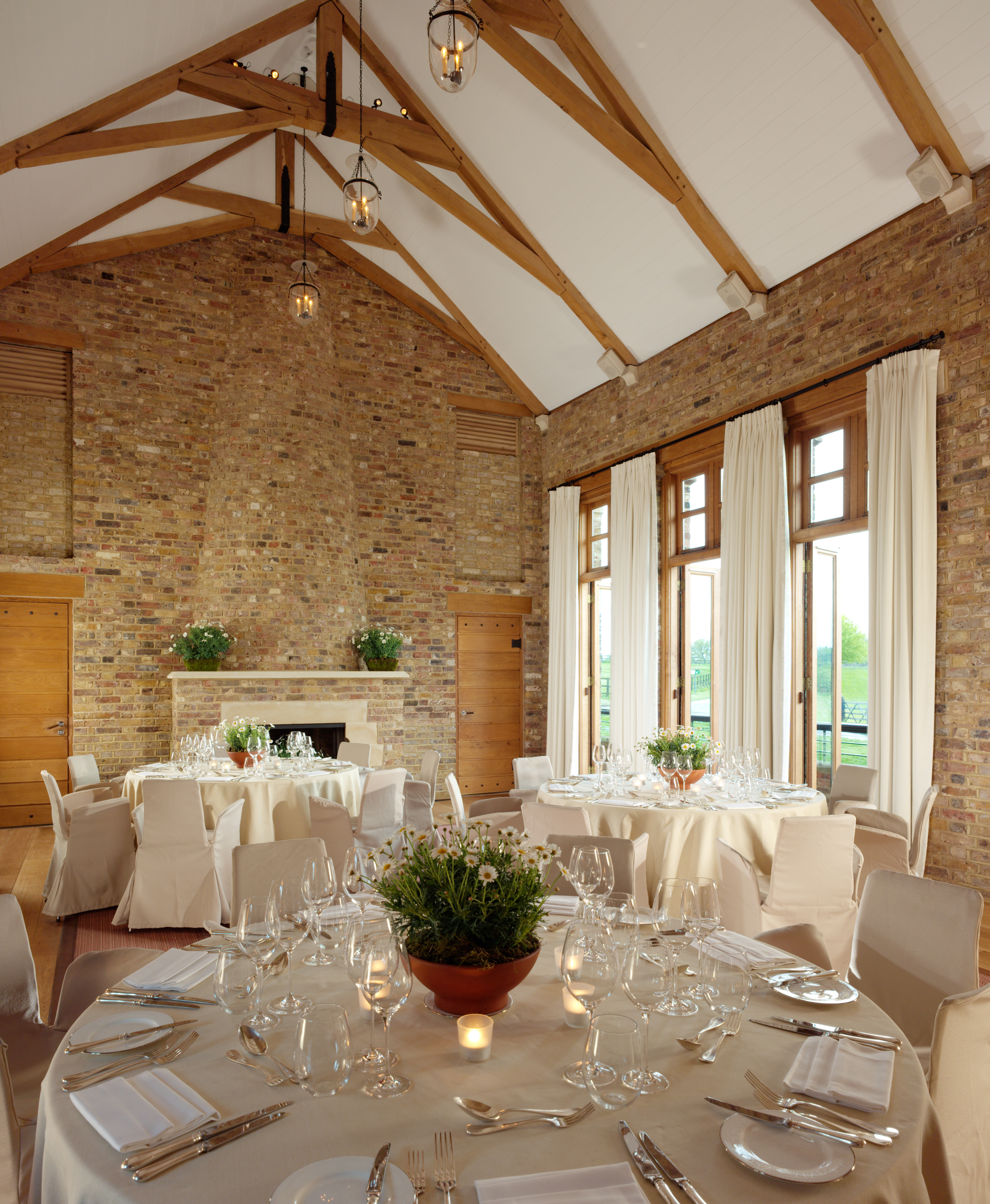 Elegant event space at The Tower House, Coworth Park with round tables and natural light.