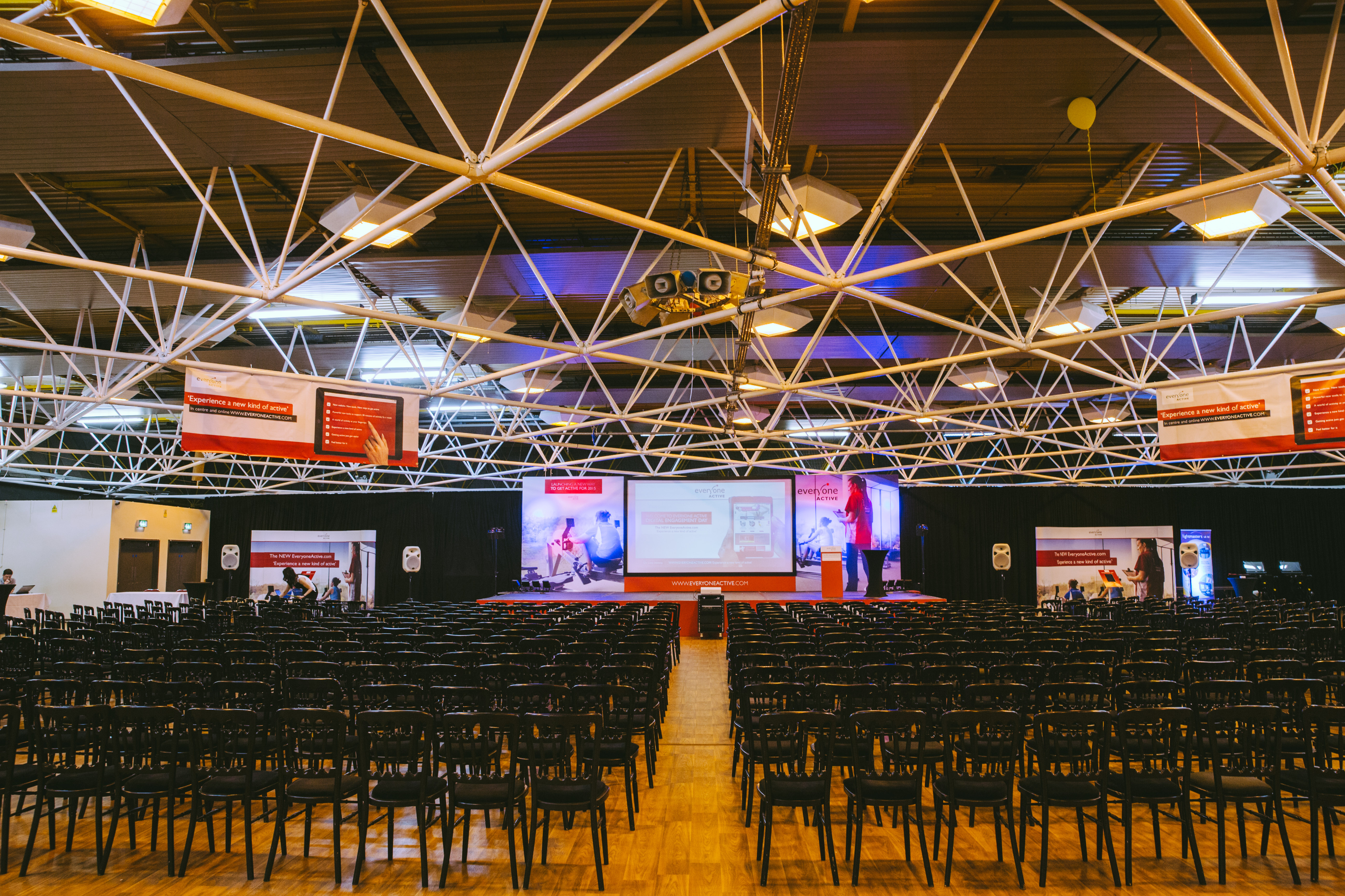 Spacious Byron Hall venue with black chairs for a professional conference setup.