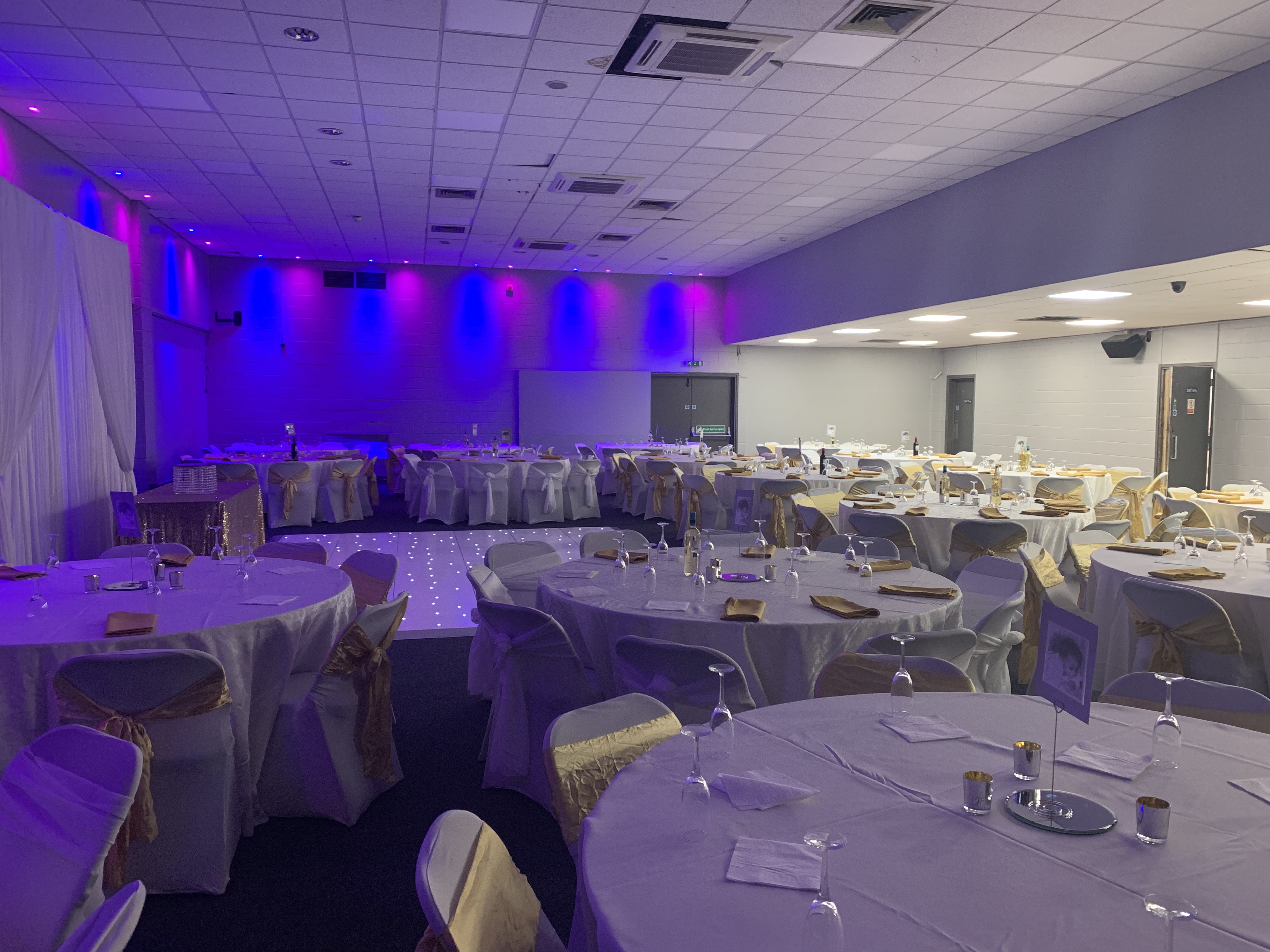 Elegant event space with round tables and purple lighting for formal gatherings.
