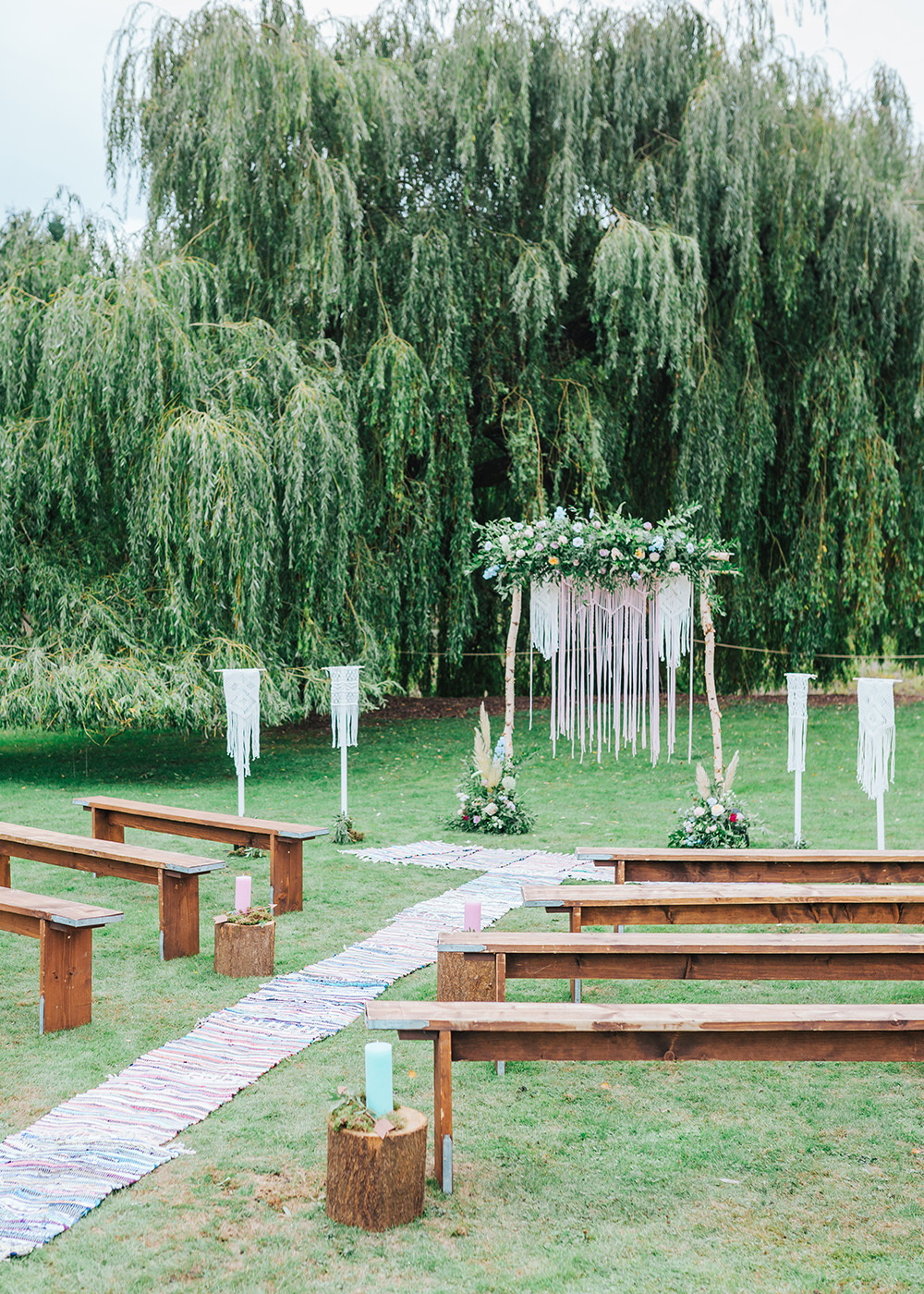 Outdoor wedding venue at Vanstone Park with floral arch and rustic wooden benches.