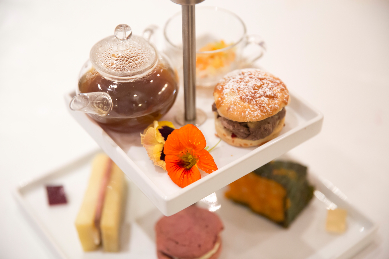 Elegant tiered serving tray for high tea at The Mansion, featuring pastries and teapot.
