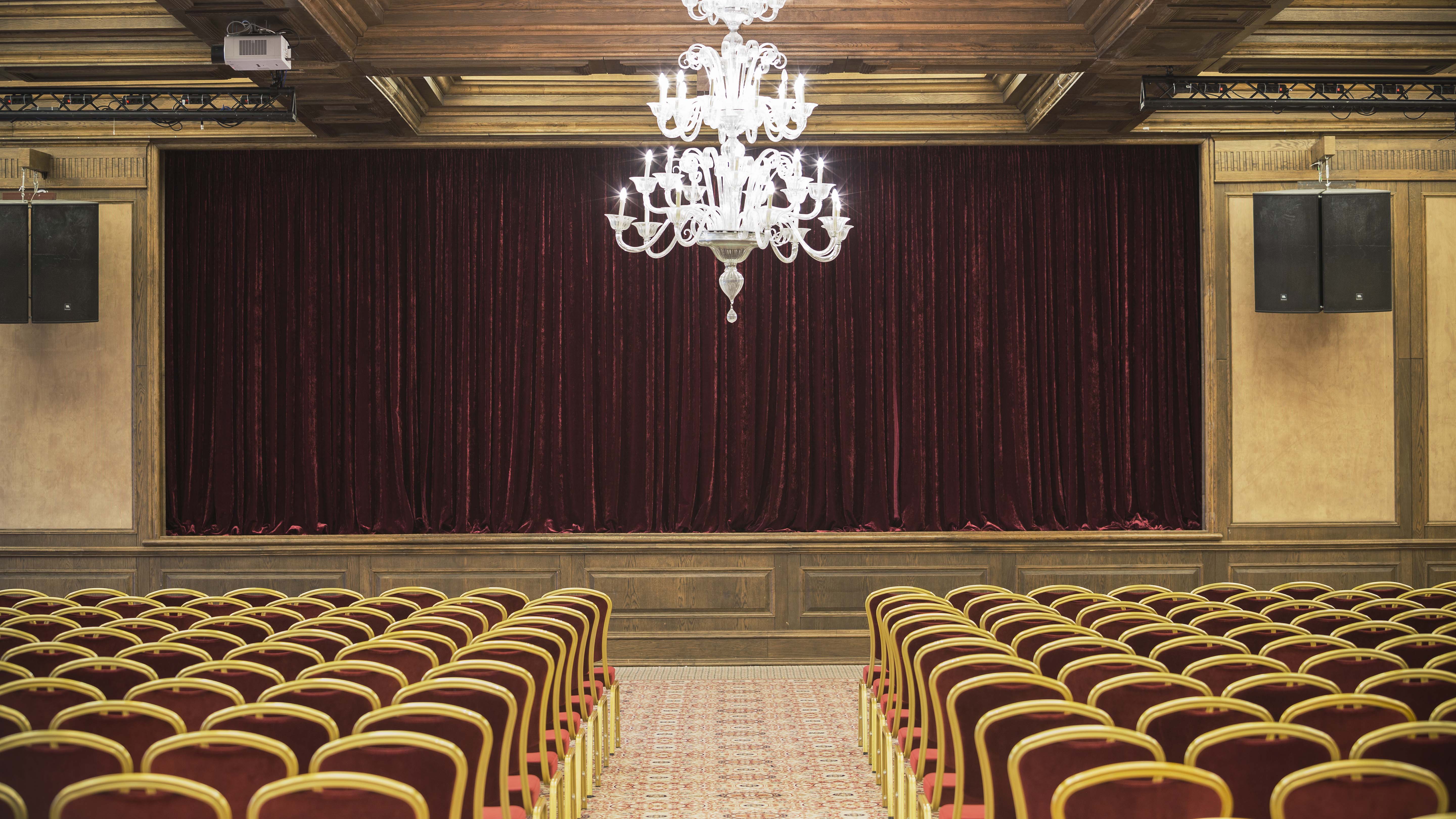 Grand Opera event space in Vilnius with burgundy curtains and elegant chandeliers.