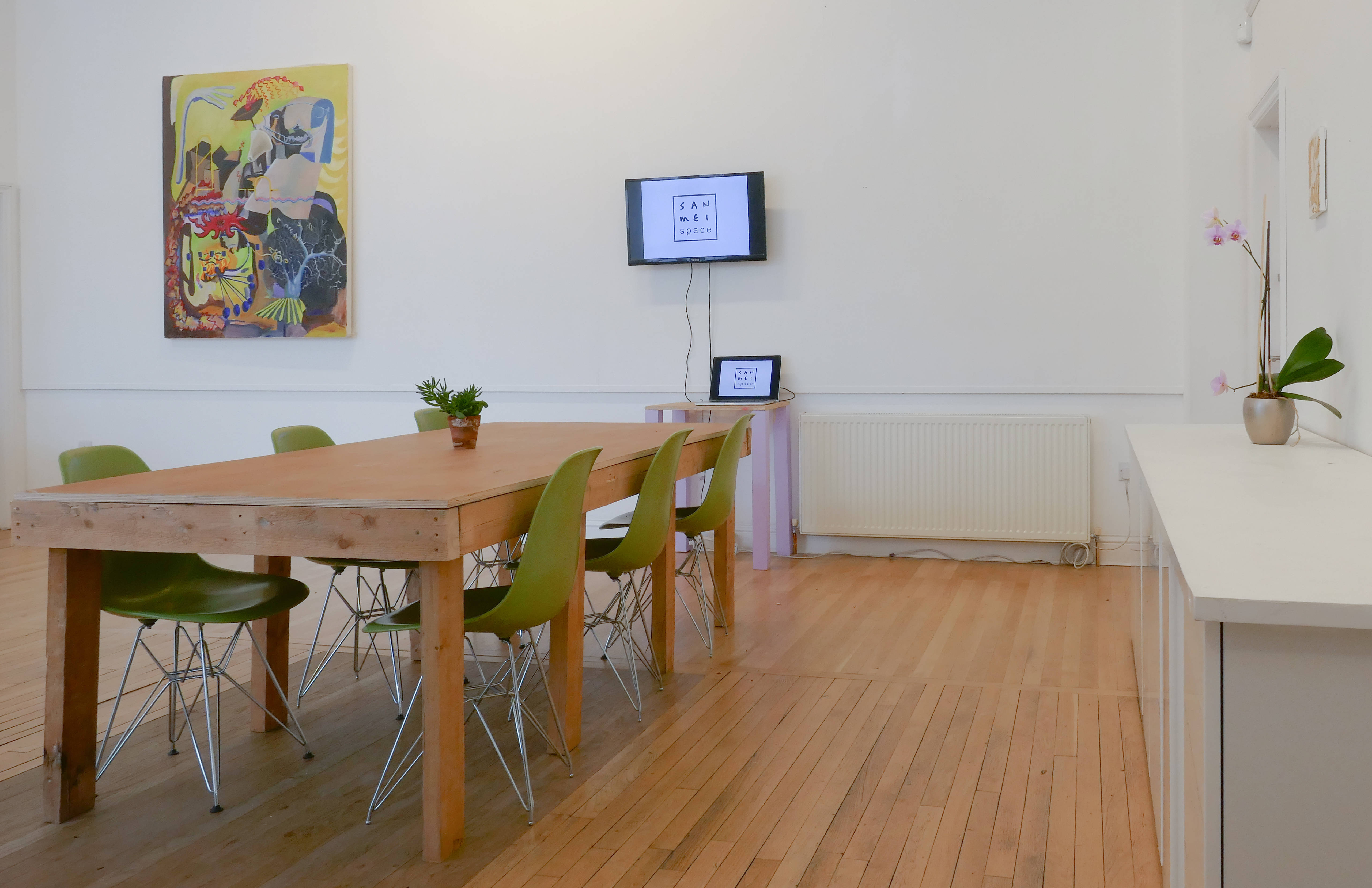 Modern meeting space with wooden table and green chairs for collaborative events.