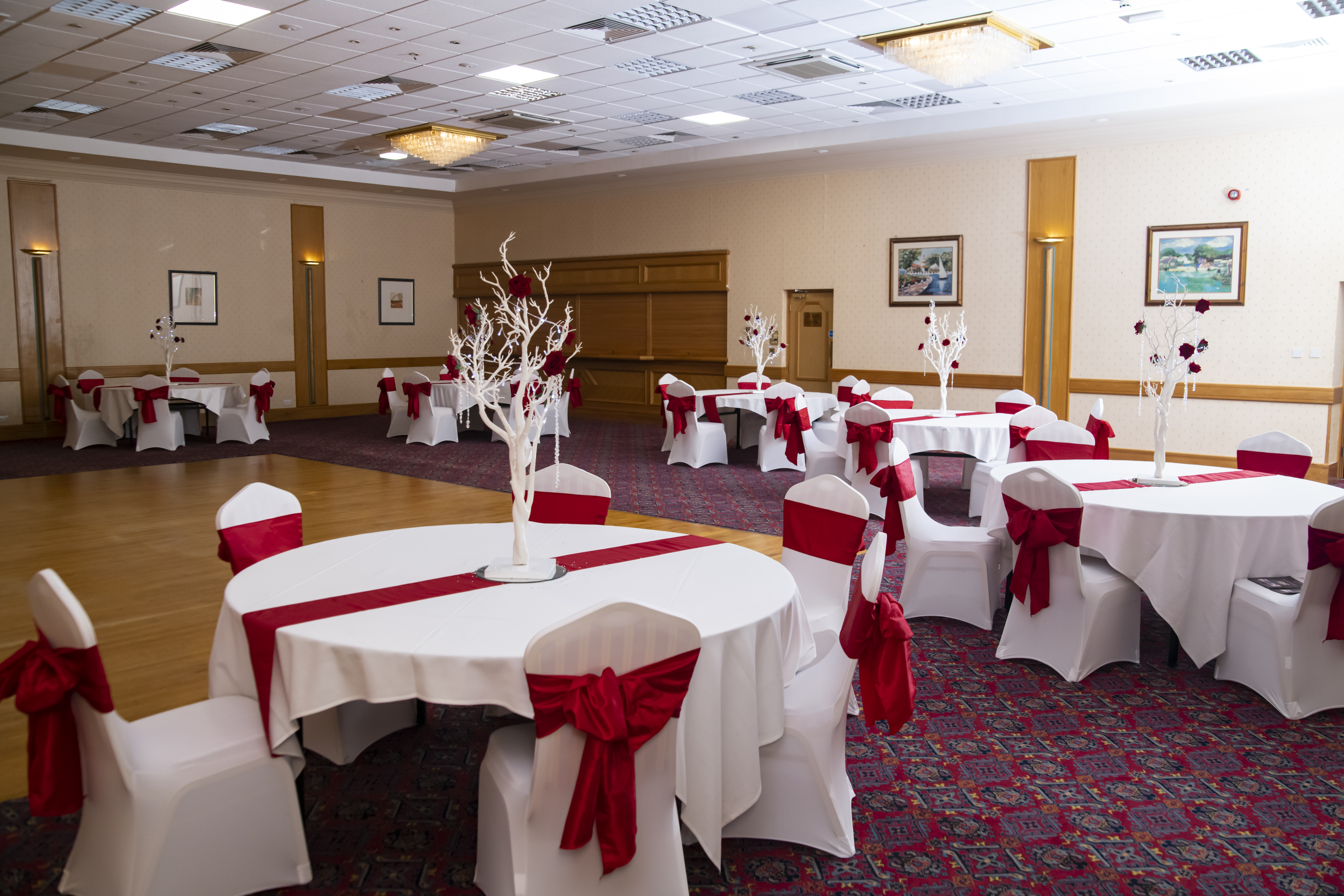 Castellan Suite at Britannia Hotel: elegant event space for weddings with round tables and red accents.